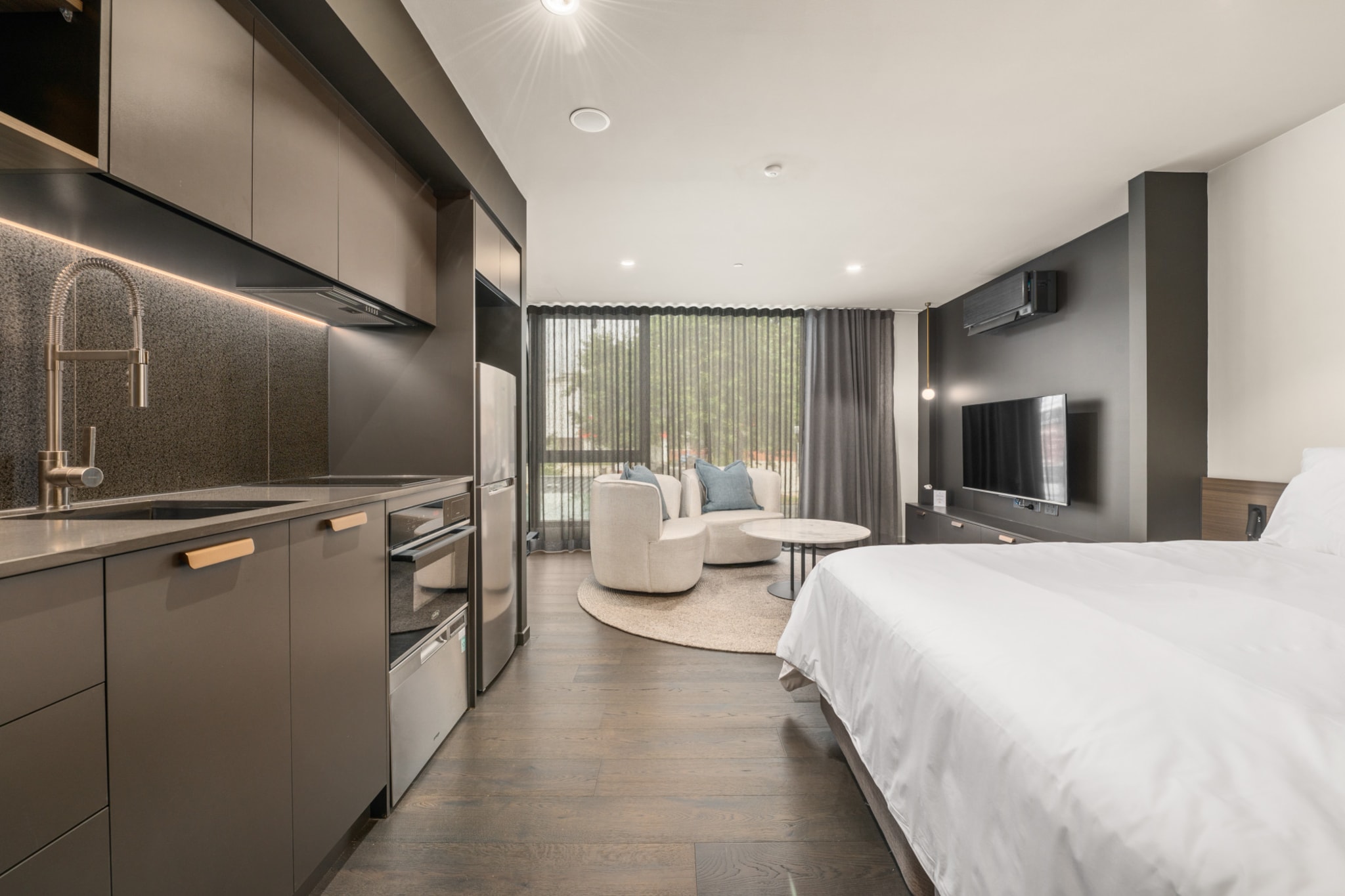 This immaculate studio, designed for both elegance and convenience, is perfect for visitors to the ACT, whether for business or leisure. The bright, modern interiors with large windows create a welcoming atmosphere. Step outside to find parks, top-notch restaurants, and public transport just moments away. With amenities like air conditioning, onsite parking, and a prime location just 7 minutes from the CBD, this accommodation is ideal for your stay in the ACT.
The space
This elegantly designed king-sized studio apartment offers a perfect blend of comfort, style, and functionality. Inside, you'll find a chic, compact kitchen and a spotless, modern bathroom. The bright, open layout features large sliding doors that lead to a communal balcony equipped with a BBQ area, dining space, and stunning views. Located in a prime area, the apartment provides easy access to parks, restaurants, shops, and public transport. Additional amenities include air conditioning, laundry facilities, and onsite parking. With self-check-in available, guests can enjoy a seamless experience from start to finish in this pristine property.
Living Space
- Couch sits 2 people
- TV with free air channels & streaming available (guests to use own credentials)
Kitchen & Dining Area
- Fully equipped with cookware, utensils and cutlery
- Oven and induction stovetop
Bathroom & Laundry
- Paid communal laundry facilities available
- Travel essentials, towels and hairdryer provided
Amenity Notes
- Split A/C (heating + cooling)
- Wi-Fi available
- No Parking
- Amenity access: access to a communal balcony with a BBQ area, dining area, and views (level 1)