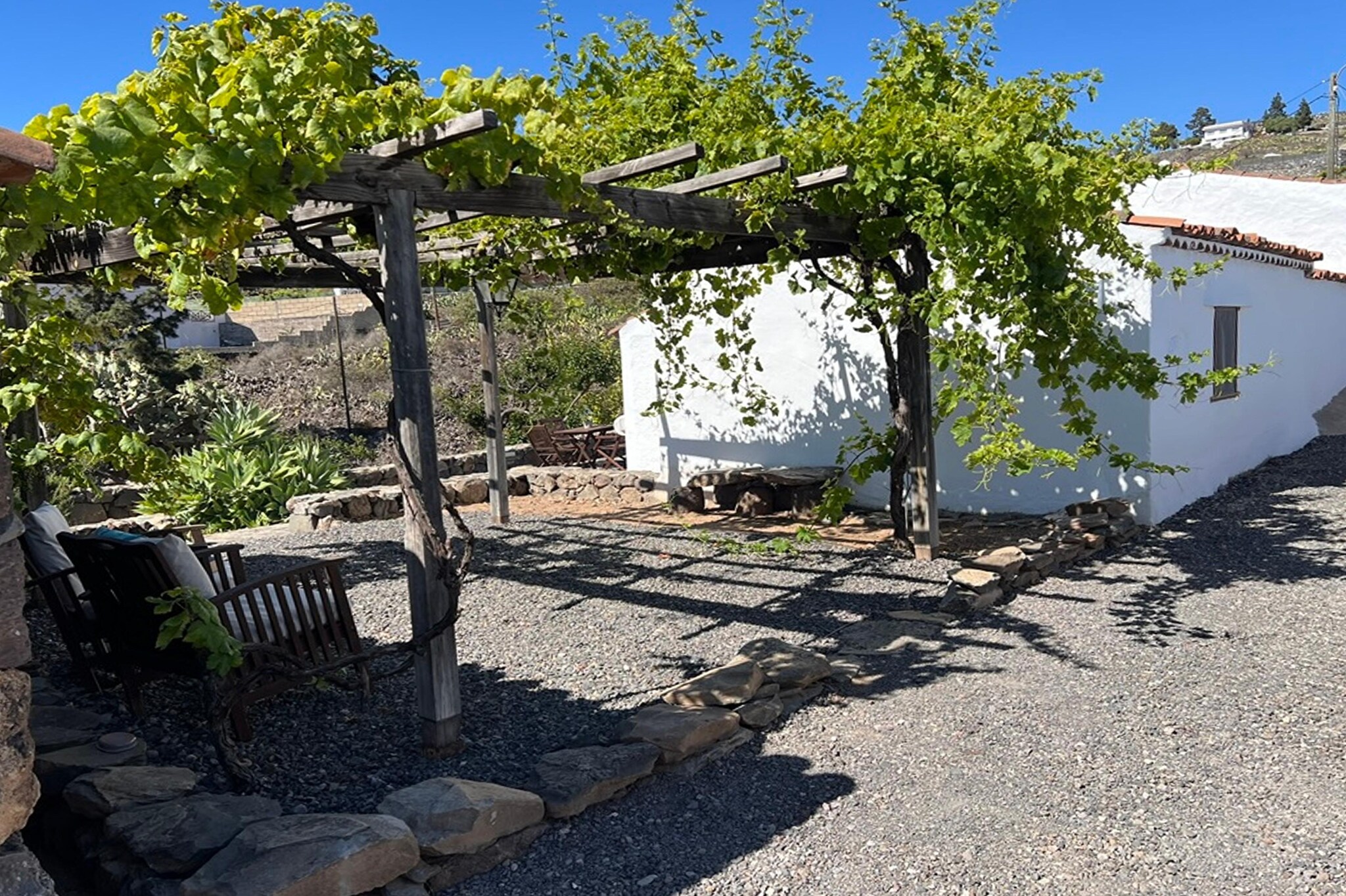 Tucked away in the historic hamlet of Taucho, this charming rural home invites you to slow down, breathe deeply and experience Tenerife as it once was. Part of the centuries-old Caserío El Estanco Viejo, the house stands among wide open spaces, orchards and gardens, lovingly restored to honour traditional Canarian architecture. With stone walls, wooden beams and terracotta tiles, it blends heritage with comfort, offering a peaceful retreat framed by sweeping views of the Atlantic, La Gomera, La Palma and even Mount Teide.
Inside, the home is warm and welcoming, featuring a bright living and dining area that opens onto a sun-kissed terrace. The fully equipped kitchen has everything you need for relaxed meals, while the three bedrooms provide flexible sleeping options for families and small groups. After a day of exploring, unwind with a film in the cosy lounge or enjoy a quiet evening on the terrace, listening to the sounds of the countryside. Practical touches like a washing room with dryer, ironing essentials, and modern amenities ensure a comfortable, worry-free stay.
Step outside to discover your private garden, complete with outdoor furniture, a BBQ corner and a private pool that stays open year-round. The setting feels worlds away from the island’s busy resorts, yet you are close enough to reach the beaches of Costa Adeje, local hiking trails, pine forests and scenic viewpoints within minutes. Whether you’re seeking tranquillity, nature or a window into Tenerife’s rural past, this beautifully restored finca offers a truly authentic and memorable escape.