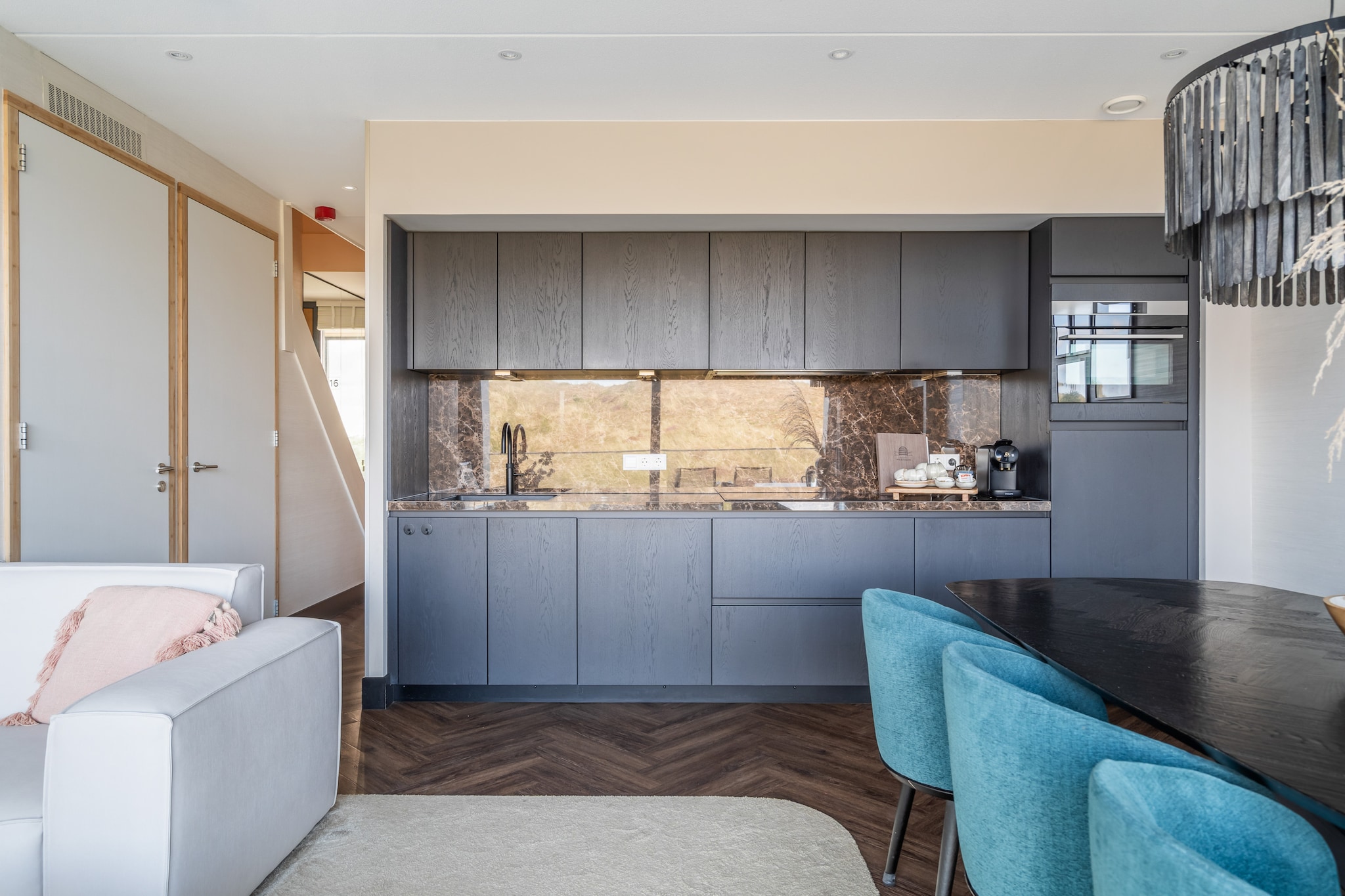 Imagine opening the doors to your balcony and being greeted by endless dunes that meet the glimmering line of the North Sea. The soft rhythm of the waves drifts through the air, mingling with the quiet beauty of your surroundings. This is Penthouse Zilt – a place where space, light, and design come together to create something extraordinary. Spread across two levels on the 2nd and 3rd floors of Residence Westduin, the penthouse exudes a refined sense of comfort. Every corner feels intentional, every detail thoughtfully chosen. The elegant furnishings, natural tones, and gentle textures give the space an effortless warmth — a home that breathes calm and sophistication. You can reach your private retreat directly from the parking garage by elevator or by the stairs, whichever you prefer.
The master bedroom is pure indulgence. It offers not just an extra-large bed but also a freestanding bathtub, perfect for slow mornings or quiet evenings spent soaking away the day. Two additional bedrooms provide flexible sleeping arrangements, with comfortable single beds that can be placed separately or together. The two modern bathrooms elevate the experience even further — one featuring your own private sauna, a haven of relaxation that turns every day into a small retreat.
Step outside, and the beauty of Sint Maartenszee unfolds before you. Within minutes, you can walk to the wide sandy beach, where dunes roll into the sea and time seems to pause. Take a bike along the coastal trails, pass through colorful flower fields in bloom, or explore charming nearby villages like Callantsoog and Petten. Each day offers a new moment to enjoy — whether it’s a peaceful sunset over the dunes or a simple breakfast on your balcony.