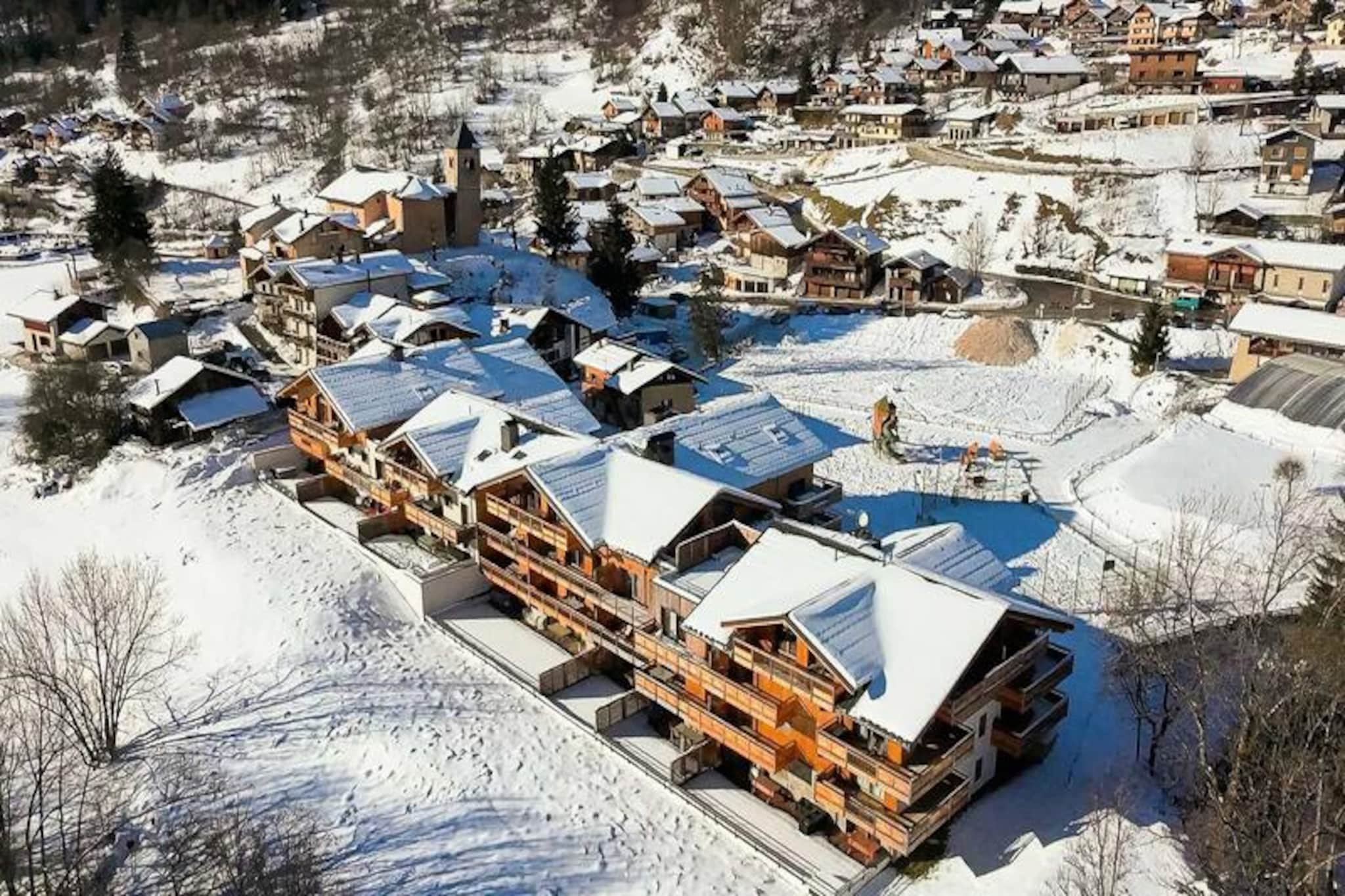 In the picturesque hamlet of Villard Dessous, where the majestic Vanoise mountains stretch endlessly across the horizon, lies a modern alpine retreat that promises both elegance and comfort. With unobstructed views of the peaks and the charming village of Champagny en Vanoise below, this residence offers a perfect blend of tranquility and convenience. Whether you’re seeking a winter wonderland or a summer escape, this location invites you to immerse yourself in the beauty of the French Alps. \n\nThe apartment, part of the newly built Terrasses de la Vanoise, boasts a spacious 102m² layout designed to accommodate up to eight guests. Featuring three north-facing bedrooms, including a family suite with bunk beds, and a luxurious bathroom with whirlpool jets, every detail has been thoughtfully crafted for relaxation. The fully equipped kitchen opens onto a cozy living room, where you can unwind after a day of adventure. Step out onto the south-facing balcony and breathe in the crisp alpine air as you marvel at the panoramic views. Additional amenities include Wi-Fi, hotel services, parking with electric charging stations, and a ski locker with a boot dryer, ensuring a seamless stay. \n\nLocated just 500 meters from shops and ski lifts, you’ll have easy access to the village’s amenities, including free municipal shuttles that connect you to Champagny-le-Haut. In summer, the nearby swimming pool and spa provide refreshing leisure options. Explore the surrounding trails, indulge in local cuisine, or simply relax in the serene alpine ambiance. With its blend of modern luxury and natural beauty, this property is your gateway to unforgettable mountain memories.