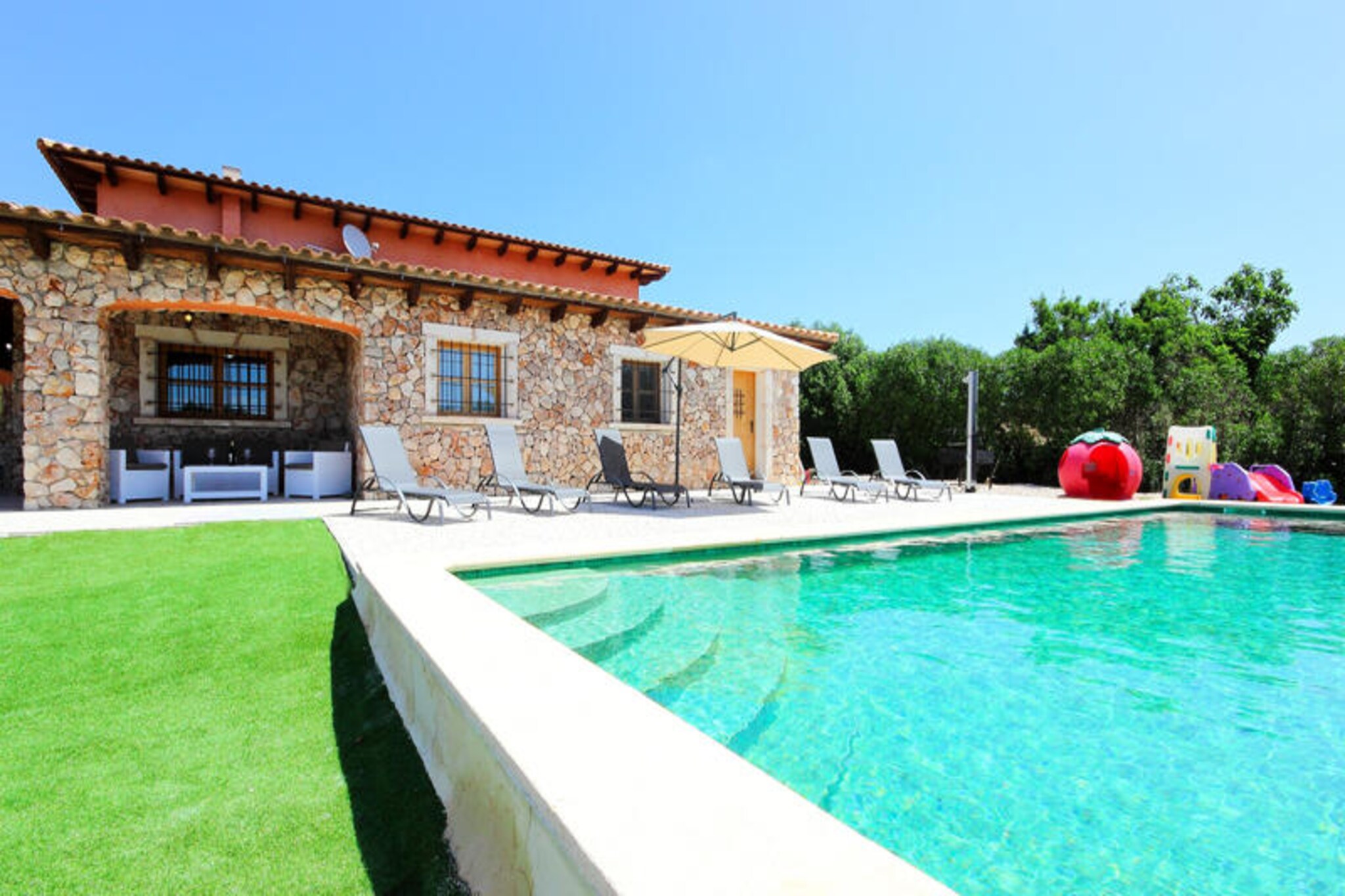 Amidst the serene countryside of Muro, this stunning Mallorcan villa invites you to experience the perfect blend of tranquility and Mediterranean charm. Surrounded by lush landscapes and far from the bustle of mass tourism, this property offers a peaceful retreat where relaxation takes center stage. Whether you’re soaking in the sun by the glistening pool or enjoying the gentle breeze on the terrace, every moment here feels like a breath of fresh air. The idyllic setting is complemented by the authentic beauty of Muro, a village steeped in tradition and local culture. \n\nSpanning an impressive 5,000 square meters, this villa is designed to accommodate up to eight guests in absolute comfort. The spacious living and dining area is tastefully furnished, featuring satellite TV and high-speed WiFi for your convenience. A fully equipped open-plan kitchen awaits, perfect for preparing delicious meals with fresh ingredients from the local market. The property boasts four inviting bedrooms and two luxurious bathrooms, one of which is en suite, ensuring ample space and privacy for all. For cooler evenings, a cozy pellet stove provides warmth and ambiance. \n\nStep outside to discover a large covered terrace ideal for al fresco dining, complete with a barbecue area to savor Mediterranean flavors. The expansive lawn and the sparkling 10x5m swimming pool are surrounded by comfortable sun loungers, offering the perfect spot to unwind. Children will delight in the selection of toys available, making this villa a family-friendly haven. The weekly visits from the gardener ensure the outdoor spaces remain pristine for your enjoyment. \n\nWith its proximity to Muro’s cobbled streets and traditional architecture, as well as spectacular beaches and exquisite dining options, this villa is a gateway to the authentic beauty of Mallorca. Whether you’re seeking a romantic escape, a family adventure, or a peaceful retreat, this property promises an unforgettable vacation in the heart of the Mediterranean.