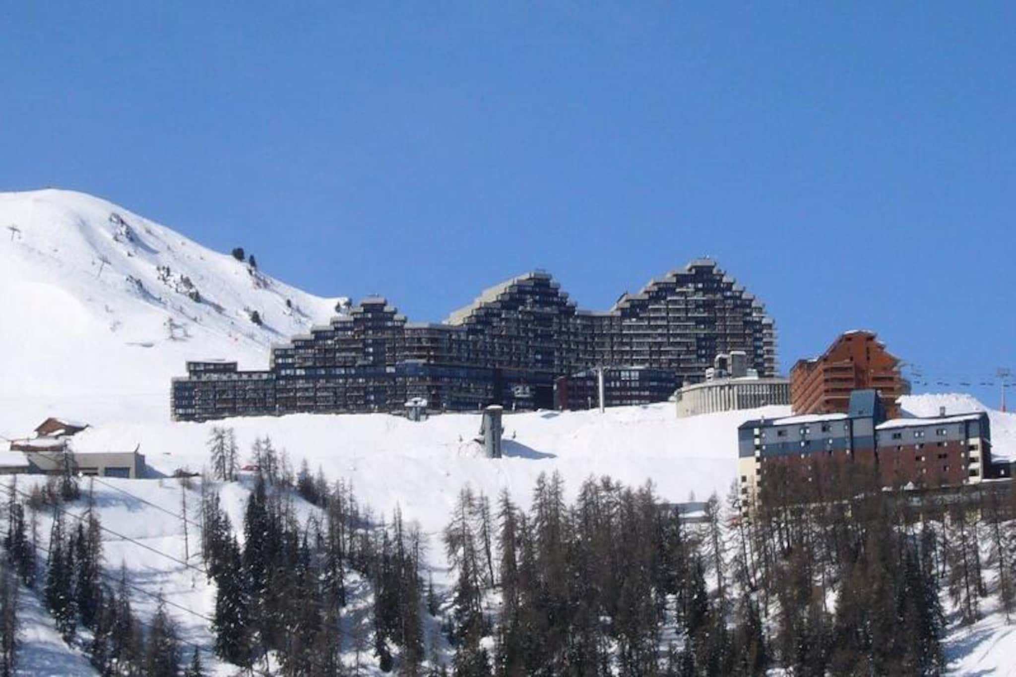 High above the Tarentaise Valley, where the crisp alpine air invigorates the senses, the Chamois Column studio offers a charming retreat within the iconic Paquebot des Neiges residence. This unique architectural gem, reminiscent of a cruise ship, is perfectly positioned for ski enthusiasts, with direct ski-in/ski-out access to the slopes and breathtaking views from its south-facing balcony. Whether you're here to carve through pristine snow or simply soak in the serene mountain atmosphere, this studio promises an unforgettable escape. \n\nDesigned for comfort and practicality, the 26m² studio accommodates up to four guests. The living area features two single sofa beds, a trundle bed, and a fold-down bed, ensuring flexible sleeping arrangements for families or small groups. A flat-screen TV provides entertainment after a day of adventure, while the open kitchen is equipped with a microwave, refrigerator, dishwasher, and electric burners, making meal preparation a breeze. The bathroom includes a bathtub for a relaxing soak, and the separate toilet adds convenience to your stay. \n\nThe Paquebot des Neiges residence boasts excellent amenities, including free outdoor parking, paid covered parking, and shops conveniently located on level G. A ski locker ensures hassle-free storage, and a free resort shuttle on the ground floor makes exploring the area effortless. For added comfort, linens, end-of-stay cleaning, and Wi-Fi access are available at an additional cost. \n\nWhether you're drawn to the thrill of the slopes or the tranquility of the mountains, the Chamois Column studio is your gateway to the beauty and adventure of the French Alps. Create lasting memories in this cozy retreat, where every detail is designed to enhance your alpine experience.