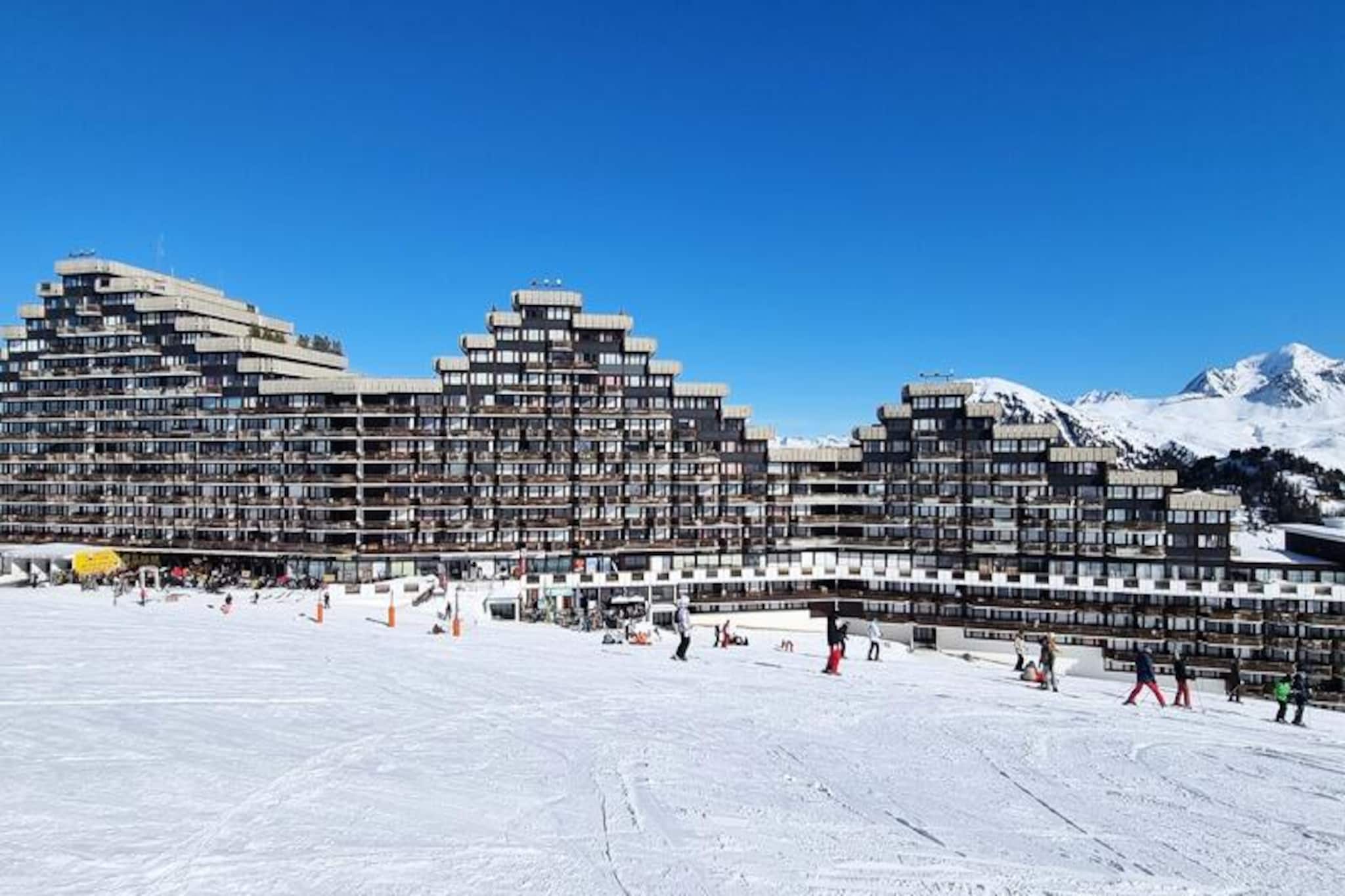High above the bustling slopes of Aime 2000, this charming studio cabin offers a unique alpine escape in the iconic Paquebot des Neiges ski resort. With its north and south exposure, the residence captures the serene beauty of the mountains while providing direct ski-in/ski-out access to the pristine slopes. Imagine waking up to the sunlit views of snowy peaks from your south-facing balcony, ready to embark on a day of thrilling adventures in the heart of the French Alps. The Zenith Column, with its distinctive architecture, ensures a truly memorable stay for all guests. \n\nThis cozy 26m² studio is thoughtfully designed to accommodate up to four people. The living room features a comfortable sofa bed (160x200 cm) and a flat-screen TV, perfect for unwinding after an active day. A separate sleeping alcove with bunk beds offers additional privacy and comfort. The kitchen, conveniently located at the entrance, is equipped with modern amenities including a combi oven, ceramic hobs, refrigerator, and dishwasher, making meal preparation a breeze. The bathroom includes a bathtub and a separate toilet, ensuring convenience for all guests. \n\nThe residence boasts exceptional facilities, including free outdoor parking and paid covered parking, ski lockers, and direct access to shops and the cable car station on level G. A free shuttle service is available on the ground floor, making it easy to explore the resort. Additional services such as Wi-Fi, baby equipment, and end-of-stay cleaning are available upon request. \n\nWhether you’re here for exhilarating ski days or tranquil evenings enjoying the alpine ambiance, this studio cabin is the perfect base for creating unforgettable memories in the French Alps. With its blend of comfort, convenience, and breathtaking views, it promises an experience that will linger long after your stay.