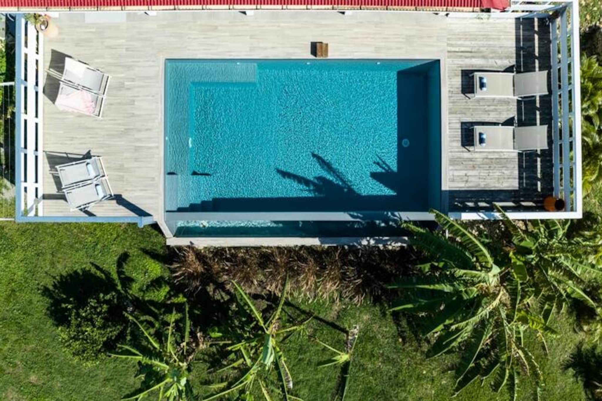 In the heart of the serene and unspoiled island of Marie-Galante, this elegant villa offers a tranquil escape with stunning sea views and a lush tropical garden. Imagine waking up to the gentle rustle of banana leaves and the soft Caribbean breeze, just minutes from pristine white sand beaches and the turquoise waters of the Atlantic. This contemporary retreat is the perfect haven for families or groups of up to nine guests seeking relaxation and adventure under the Guadeloupe sun.
Spanning 160 m², the villa features four air-conditioned bedrooms, each with its own en-suite bathroom, ensuring privacy and comfort for all. The upstairs bedroom provides an added touch of seclusion, while the ground floor boasts a bright, open-plan living area with a modern, fully equipped kitchen and a spacious lounge. Step outside onto the inviting terrace, where a large dining table and cozy seating area await for al fresco meals and sunset cocktails. The private pool, surrounded by vibrant tropical foliage, is the centerpiece of the garden, offering a refreshing oasis with breathtaking sea views.
Located in Grand-Bourg, the villa is just a short drive from local markets, Creole restaurants, and the island’s most famous beaches, including Anse Canot and La Feuillère, a kitesurfing paradise. Explore nearby distilleries, hike through sugarcane fields, or enjoy live music on the beach. With a dedicated concierge to assist with excursions, vehicle rentals, and personalized recommendations, every detail is tailored to create an unforgettable stay.
Whether you’re lounging by the pool, savoring local delicacies, or discovering the island’s natural beauty, this villa promises a Caribbean getaway filled with serenity, comfort, and discovery.
