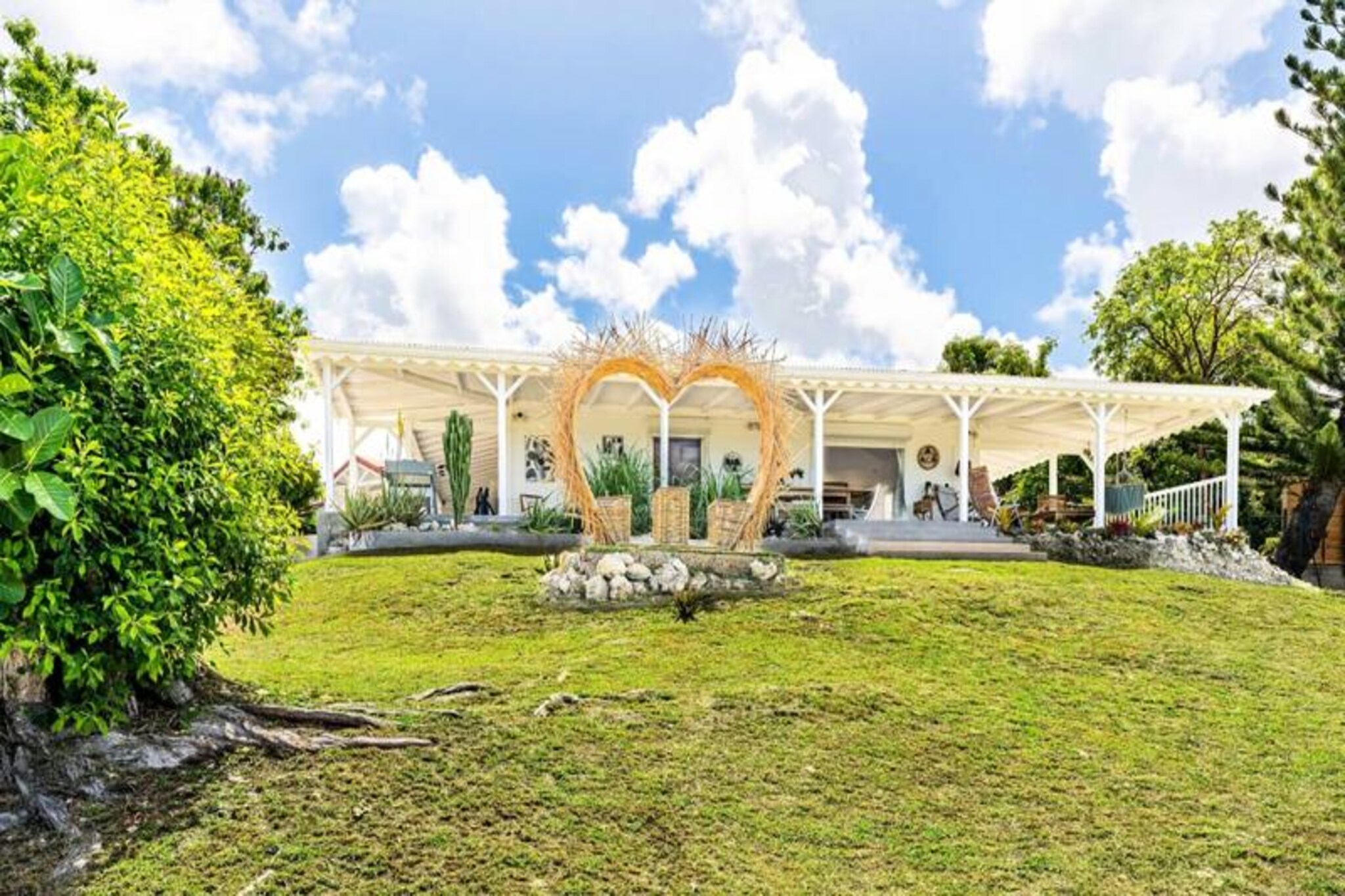 Perched on the serene hills above Grand Bourg, Villa Moca is a haven of elegance and tranquility, offering breathtaking views of the Caribbean Sea and mesmerizing sunsets. Surrounded by a lush 3,500m² garden, this traditional villa invites you to escape into a world of relaxation and natural beauty, where the gentle sea breeze and vibrant tropical ambiance create the perfect retreat.
Designed to accommodate up to eight guests, the villa boasts four air-conditioned bedrooms, each with its own en-suite bathroom featuring a walk-in shower. The heart of the home is the fully equipped kitchen, seamlessly opening onto the pool area. Here, a private salt-water pool glistens under the Caribbean sun, surrounded by comfortable deckchairs and a shaded lounge area for ultimate relaxation. The expansive terrace, with its large dining table, sets the stage for unforgettable meals, while a charcoal barbecue invites you to savor outdoor grilling experiences. A second terrace offers panoramic views of neighboring islands, making it the ideal spot to enjoy a sunset cocktail.
Located just five minutes from the charming town of Grand Bourg, Villa Moca provides easy access to local amenities, including supermarkets, bakeries, and vibrant Creole markets. The island’s pristine beaches, such as La Feuillère and Anse Canot, are perfect for swimming, sunbathing, or simply soaking in the tranquil surroundings. Nature enthusiasts will delight in exploring the island’s hiking trails and sugarcane fields, which add to the unique charm of Marie-Galante.
Whether you’re seeking a peaceful getaway or an adventure-filled holiday, Villa Moca offers the perfect blend of comfort, luxury, and authentic Caribbean charm. Let the magic of Guadeloupe captivate you as you create unforgettable memories in this idyllic setting.
