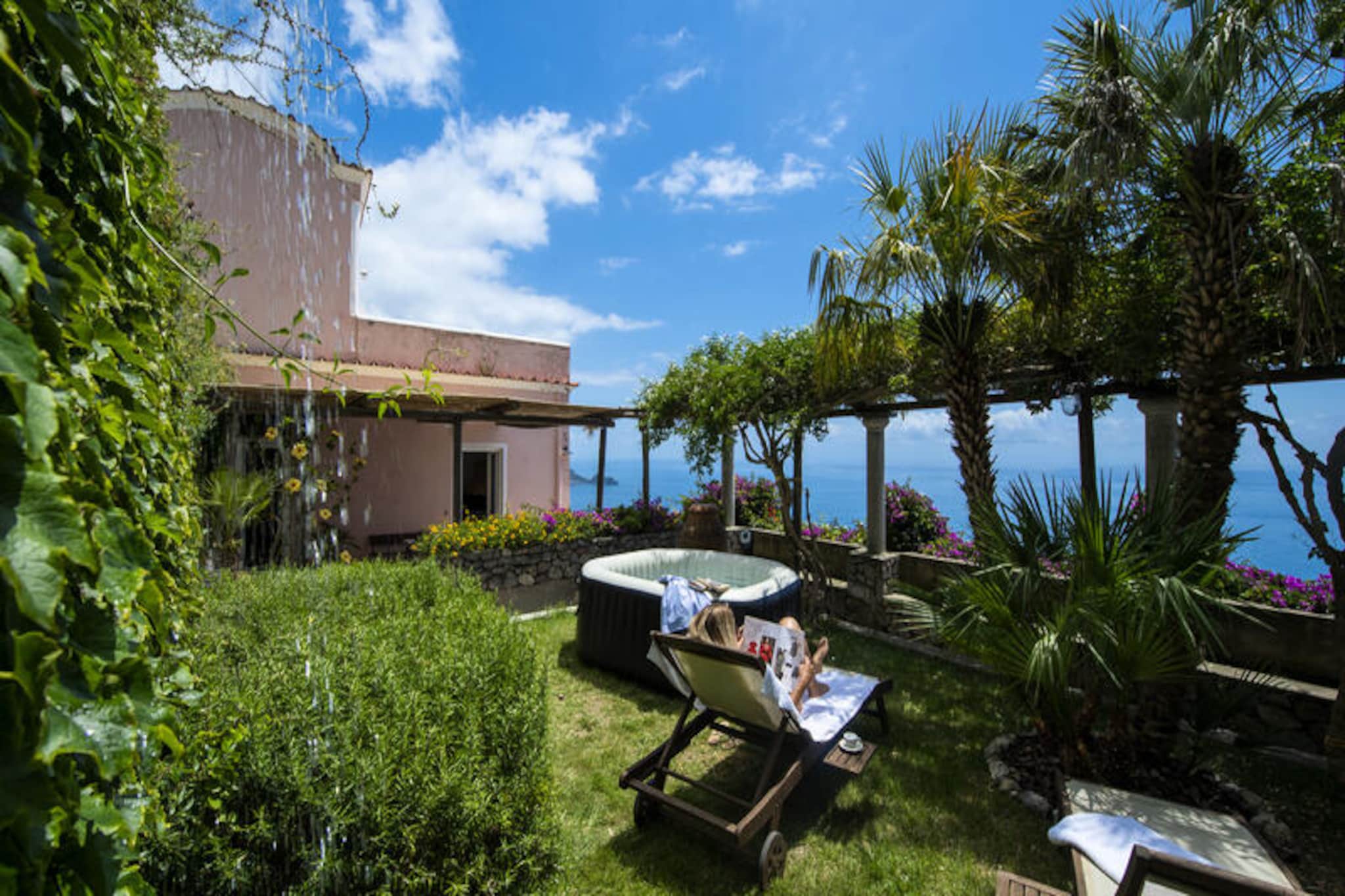 Perched above the shimmering Amalfi Coast, Casale Fralisa is a luminous and elegant villa that blends timeless charm with modern comforts. From its elevated position, the property offers breathtaking views of the Tyrrhenian Sea, creating a serene retreat where every moment feels like a postcard. The villa’s refined architecture and tasteful furnishings are complemented by a private garden and a sea-view jacuzzi, inviting guests to unwind in unparalleled beauty. Whether you’re sipping your morning espresso on the terrace or soaking in the warm waters of the jacuzzi, the scenery is sure to captivate your heart. \n\nSpread across three levels, the villa is designed to accommodate up to eight guests with ease. The ground floor features two double bedrooms, one with en-suite access, and a private bathroom. Ascend eight steps to the first floor, where a spacious open-plan living area awaits, complete with wall-hung sofas, a cozy fireplace, and a fully equipped kitchen. The terrace on this level is an outdoor oasis, boasting a dining area, sun loungers, a barbecue, and a jacuzzi that takes approximately 24 hours to warm up. On the upper floor, you’ll find a panoramic terrace and a romantic double bedroom with its own private sea-view terrace, perfect for stargazing or quiet reflection. \n\nCasale Fralisa’s location in Praiano is ideal for exploring the Amalfi Coast. Within a short walk, you’ll find charming restaurants like Moressa and Kasai, a grocery store, and convenient bus stops for local and SITA routes. For beach lovers, the picturesque La Praia beach is just a 20-minute walk away. Private parking is available upon request, making it easy to explore nearby gems like Positano, Amalfi, and Ravello. \n\nWhether you’re seeking a romantic getaway or a family escape, Casale Fralisa offers an unforgettable experience where the beauty of the Amalfi Coast becomes your daily backdrop.