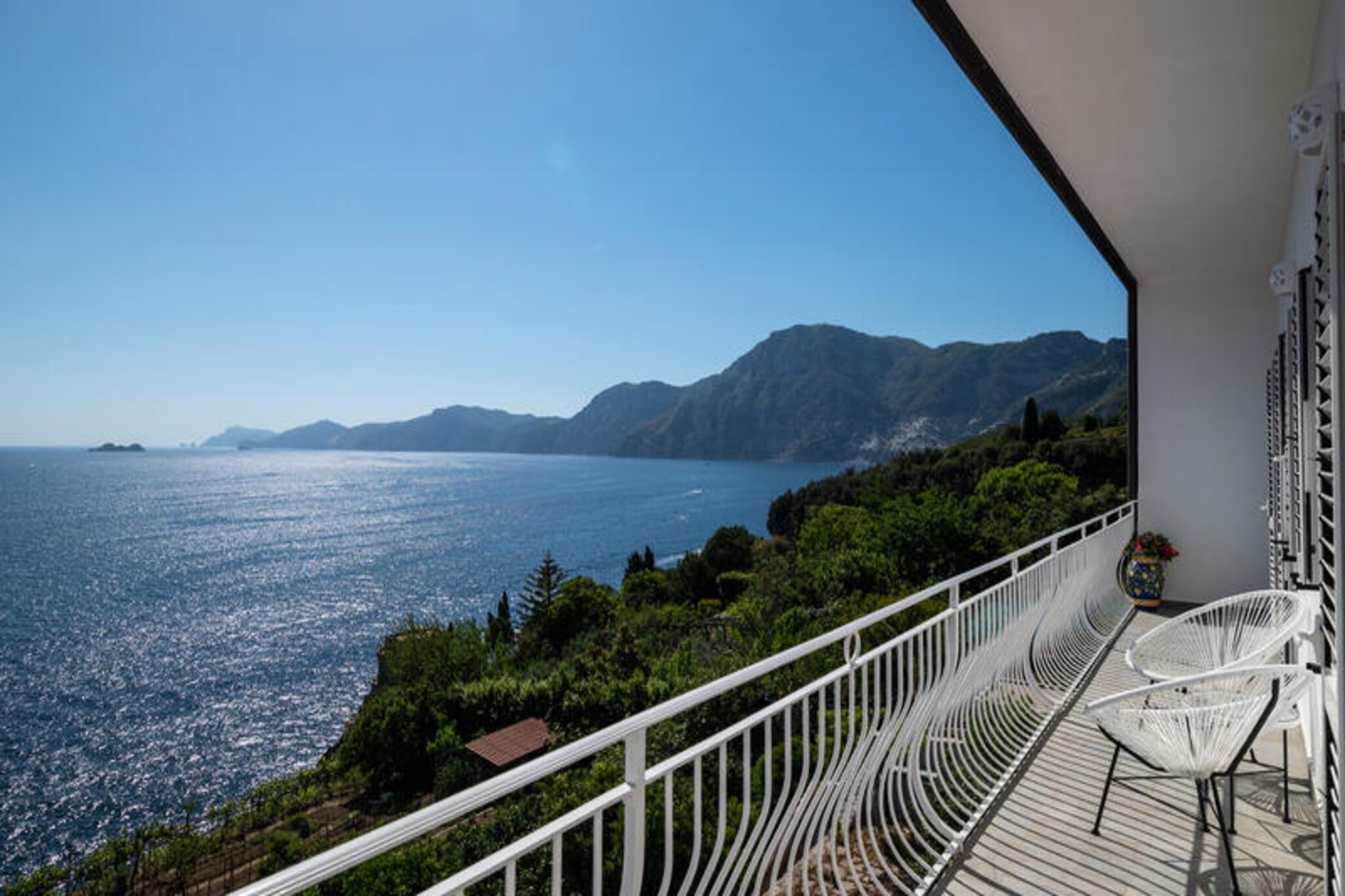 Perched on the western side of Praiano, Casa Clara offers an enchanting retreat along the Amalfi Coast, where the azure sea meets the golden hues of the Italian sun. This recently renovated gem invites you to immerse yourself in its serene atmosphere, boasting breathtaking views of Positano and Capri. The tranquil setting, combined with its proximity to the town center, makes it an ideal choice for those seeking both relaxation and convenience. Here, the sunsets are nothing short of magical, painting the sky with vibrant colors that will linger in your memory forever.\n\nCasa Clara is thoughtfully designed to accommodate up to four guests, making it perfect for families or couples traveling together. The villa features two spacious bedrooms, each with its own en-suite bathroom, ensuring privacy and comfort. The open-plan living area is adorned with large windows that frame the stunning sea views, while the fully equipped kitchen and dining space provide everything you need for home-cooked meals. Modern amenities such as Wi-Fi, air conditioning, and a cozy lounge area ensure a comfortable stay throughout your visit.\n\nA short walk from the villa leads you to the heart of Praiano, where you’ll find charming restaurants, bars, and a grocery store. For beach lovers, the famous One Fire Beach Club is just a 15-minute walk away, accessible via scenic steps that wind through the village. The villa’s unique location, accessible only by foot, enhances the sense of tranquility and connection to nature, allowing you to fully embrace the beauty of the Amalfi Coast.\n\nWhether you’re savoring a glass of wine on the sea-view terrace or exploring the nearby attractions, Casa Clara promises an unforgettable escape filled with Italian charm, stunning vistas, and the soothing rhythm of coastal life.
