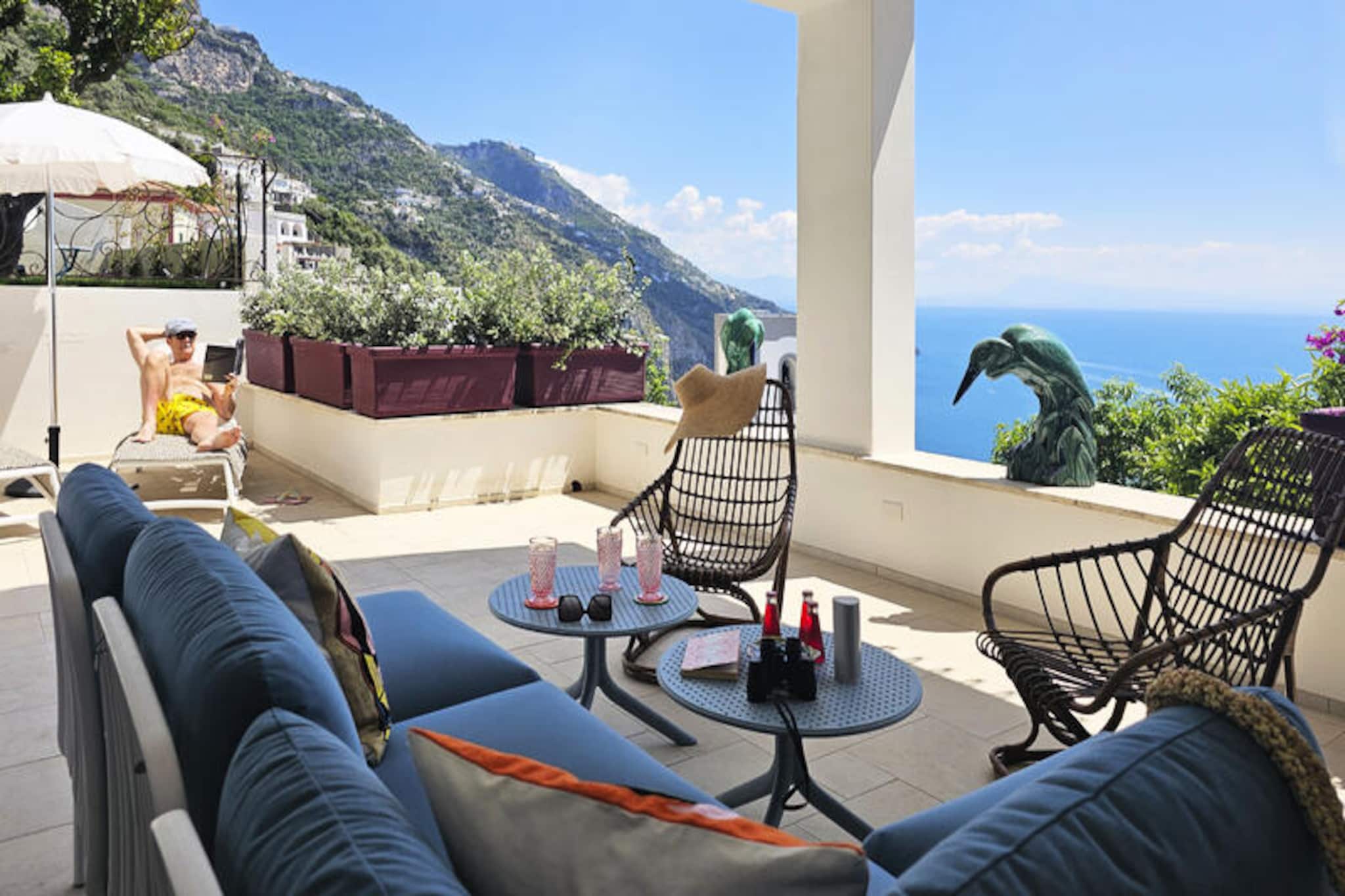 Perched on the eastern slopes of Praiano, Villa Grá is a masterpiece of elegance and charm, offering breathtaking views of the Mediterranean Sea and the iconic bell tower of the local church. Inspired by the Irish word for 'love,' this villa embodies its name through every detail, creating a serene retreat that harmonizes with the beauty of the Amalfi Coast. From the moment you arrive, you’ll be captivated by the lush garden shaded by fruit trees and the expansive terrace that invites you to soak in the coastal splendor.  
                       The villa’s interiors are a tribute to local craftsmanship, featuring hand-painted floors with Amalfi motifs, a bespoke kitchen, and exquisitely finished bathrooms. Carefully curated antique and mid-century furnishings, Murano glass pendant lights, and original artworks add a touch of timeless sophistication. Designed on a single floor, the villa boasts two queen-size bedrooms—one with direct terrace access and the other with uninterrupted sea views—alongside two elegant bathrooms with showers. The charming living room and ceramic dining table on the veranda complete the picture of refined comfort.  
                       Villa Grá’s location in the heart of Praiano offers both tranquility and convenience. A short walk leads you to local restaurants, a grocery store, and bus stops, while the enchanting La Praia Beach is just a 25-minute stroll away. Here, you can savor fresh seafood at renowned eateries or simply bask in the sun. For those arriving by car, private parking is available nearby for a fee, and porterage services can be arranged to ease your arrival.  
                       Whether you’re seeking a romantic escape or a luxurious getaway, Villa Grá promises an unforgettable experience, blending the timeless allure of the Amalfi Coast with unparalleled comfort and style.