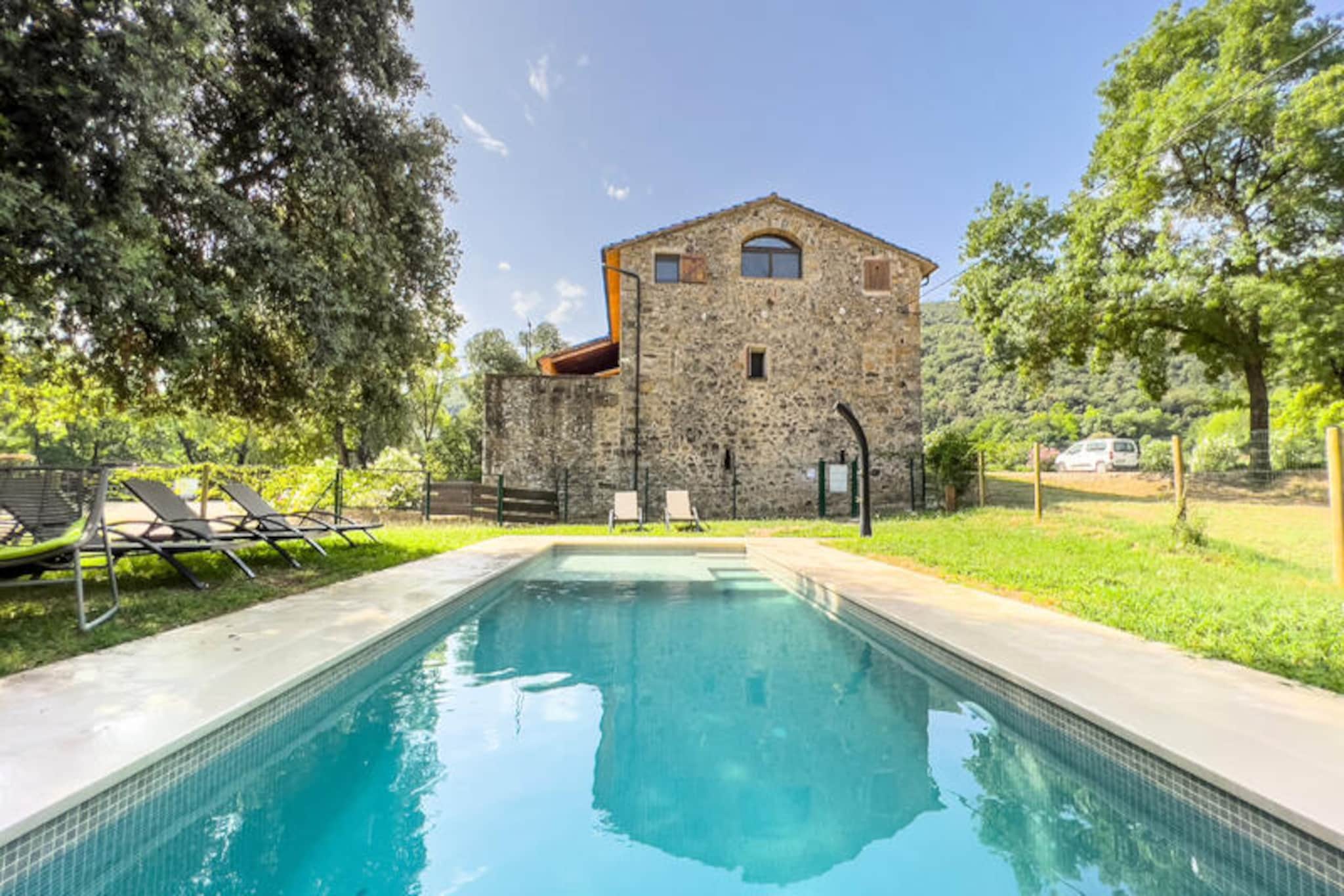In the heart of Catalonia's lush countryside, Can Blanc de Montagut invites you to experience the charm of a traditional farmhouse surrounded by the natural beauty of the Garrotxa Volcanic Zone. Here, amidst rolling hills and the gentle flow of the Fluvià River, you’ll find a serene escape perfect for families and groups seeking both adventure and relaxation. Wake up to the sound of birdsong, enjoy a morning coffee on your private terrace, and set out to explore the countless hiking trails that begin right at your doorstep.
This beautifully restored farmhouse offers a spacious and welcoming retreat. The fully equipped kitchen, with its views of the surrounding fields, is perfect for preparing meals to share at the large dining table. Cozy evenings await by the wood-burning stove in the charming living area, while the three comfortable bedrooms, including a master suite with a seating area, promise restful nights. Outside, the private garden and terrace provide a peaceful spot to unwind, while the shared swimming pool and barbecue area are ideal for sunny afternoons and al fresco dining.
The location is a gateway to the wonders of La Garrotxa. Within a short drive, you can visit the medieval town of Besalú, the basalt cliffs of Castellfollit de la Roca, or the beech forest of Fageda d'en Jordà. For outdoor enthusiasts, the nearby Croscat and Santa Margarida volcanoes offer breathtaking hikes, and the crystal-clear rivers of Sadernes are perfect for a refreshing swim. Whether you’re exploring ancient villages, savoring local cuisine, or simply enjoying the tranquility of the countryside, Can Blanc de Montagut is your ideal base for an unforgettable Catalan getaway.