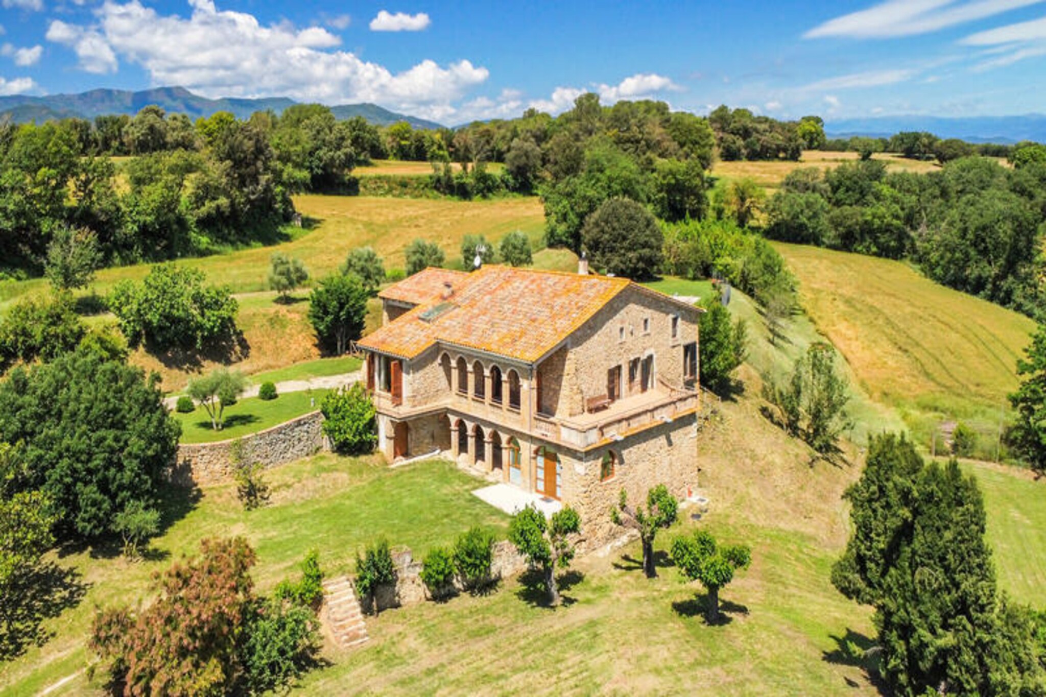 Step into the heart of Catalonia and discover Mas Maria Carmen Dalmau, a beautifully restored 18th-century country house in the picturesque village of Ravos del Terri. Surrounded by rolling countryside and medieval charm, this authentic masia offers a serene escape for families, friends, and cycling enthusiasts alike. With its perfect blend of rustic character and modern comforts, this property invites you to experience the timeless beauty of Girona’s rural landscapes.
The house boasts five thoughtfully designed bedrooms, each furnished with brand-new single beds for ultimate comfort. Two of the bedrooms are conveniently located on the same level as the kitchen, dining room, and living area, making it ideal for guests who prefer to avoid stairs. The spacious dining room, complete with a large table for 12, opens onto a south-facing balcony with breathtaking views of the medieval castle. The fully equipped kitchen, featuring a fireplace and ample storage, is perfect for preparing meals after a day of exploration. Upstairs, you’ll find a pool table and additional bedrooms, while a separate garden-access apartment offers privacy for larger groups. The expansive garden includes a saltwater pool, sun loungers, a ping-pong table, and plenty of space for outdoor games.
Cycling enthusiasts will appreciate the property’s proximity to Girona’s renowned cycling routes, while the medieval charm of Ravos del Terri and nearby Banyoles provide endless opportunities for cultural and natural exploration. Whether you’re relaxing by the pool, dining al fresco under the covered terrace, or taking in the views from the balcony, Mas Maria Carmen Dalmau promises an unforgettable Catalan getaway. Book your stay today and immerse yourself in the beauty and tranquility of this unique countryside retreat.