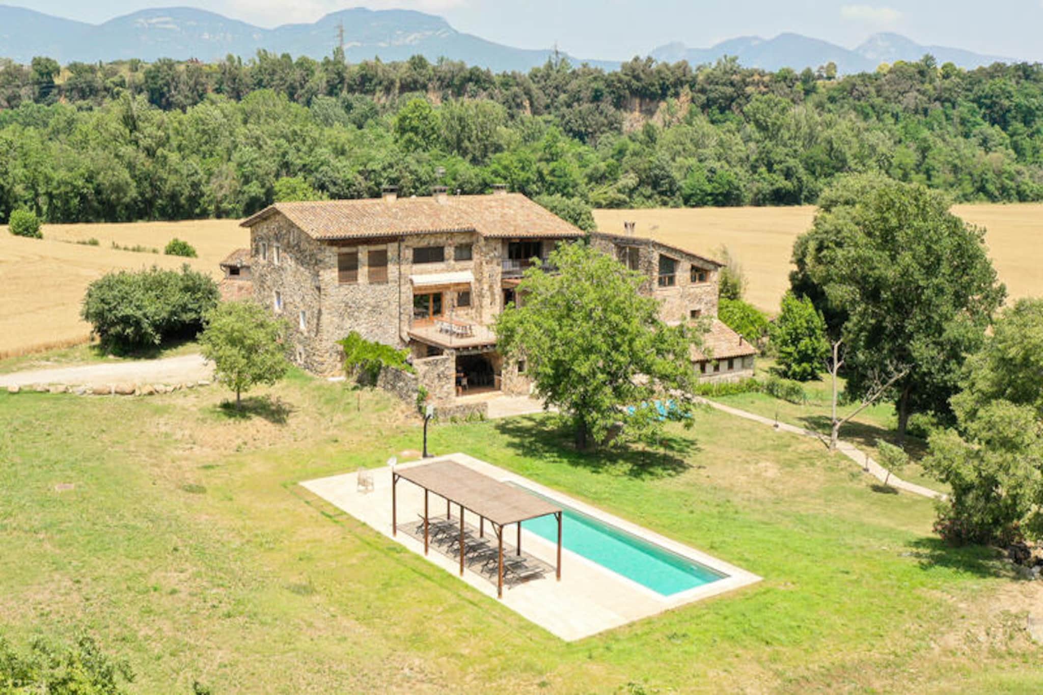 In a serene valley along the River Fluvia, Can Riera de Montagut invites you to experience the charm of a restored 16th-century masia nestled within the breathtaking La Garrotxa Natural Park. This historic farmhouse combines timeless elegance with modern comforts, offering a tranquil retreat for families, friends, or groups seeking a unique escape in the heart of Catalonia. Surrounded by lush greenery and rolling hills, its peaceful setting is ideal for reconnecting with nature or simply unwinding in style. \n\nThe property boasts five luxurious suites, each with its own en-suite bathroom, ensuring privacy and comfort for all guests. The interiors blend contemporary design with authentic details, creating a warm and inviting atmosphere. A spacious kitchen equipped with dual ovens, hobs, dishwashers, and a wood-fired oven makes meal preparation a delight, while the expansive dining room is perfect for shared moments over dinner or games. Outdoors, the newly installed saltwater pool offers a refreshing escape, complete with a shallow section for children and a sun-drenched deck for relaxation. The garden features a barbecue area and a pizza oven, ideal for al fresco dining under the walnut tree or on the south-facing terrace. \n\nLocated within easy reach of La Garrotxa’s volcanic landscapes, charming villages, and cycling trails, Can Riera de Montagut is a gateway to adventure. Explore the nearby hiking paths, visit medieval towns, or enjoy local Catalan cuisine at nearby markets. Cyclists will appreciate the repair station and secure storage, while the activity room caters to workshops, yoga sessions, or group gatherings. \n\nWhether you’re seeking a peaceful retreat, an active holiday, or a memorable celebration, Can Riera de Montagut offers an unparalleled blend of history, comfort, and natural beauty. Make lasting memories in this enchanting corner of Spain.