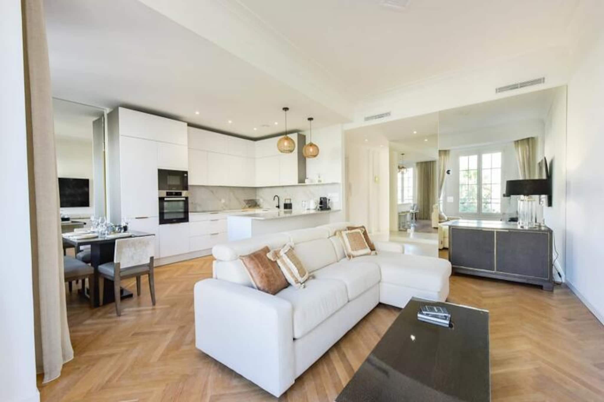 Step into a world of refined elegance and coastal charm with this luxurious 128m² apartment in the heart of Cannes. Just 100 meters from the iconic Croisette and its golden beaches, this property offers a serene escape while keeping you close to the vibrant pulse of the city. Imagine waking up to the gentle Mediterranean breeze, sipping coffee on your private balcony, and strolling to the azure waters within minutes. Whether you’re here for leisure or business, this apartment promises an unforgettable stay in one of France’s most glamorous destinations. \n\nDesigned with both comfort and style in mind, the apartment features three en-suite bedrooms, each with its own shower room, smart TV, and ample storage. The master suite boasts a king-size bed, a dressing room, and a desk area, perfect for unwinding or catching up on work. The spacious living/dining area is adorned with hardwood floors and ceiling moldings, seamlessly blending authentic charm with modern sophistication. A fully equipped open-plan kitchen invites you to prepare meals with ease, while double-glazed windows ensure peaceful nights. With air conditioning throughout and high-quality materials used in every detail, this residence is a true haven of luxury. \n\nSituated at the bottom of Avenue de Madrid, the apartment offers convenient access to local amenities such as bakeries, grocery stores, and cafes, all within walking distance. The Palais des Festivals is less than fifteen minutes away, making it ideal for those attending events or exploring Cannes’ cultural highlights. The historic Suquet district, with its winding streets and panoramic views, is just a short stroll away. For those seeking adventure, Nice Côte d'Azur Airport is only 30 minutes by car, and the Cannes train station is easily accessible. \n\nChoose this apartment for its unbeatable location, exquisite design, and proximity to everything Cannes has to offer. Whether you’re here to soak up the sun, indulge in fine dining, or attend world-class events, this property is your gateway to the best of the French Riviera.