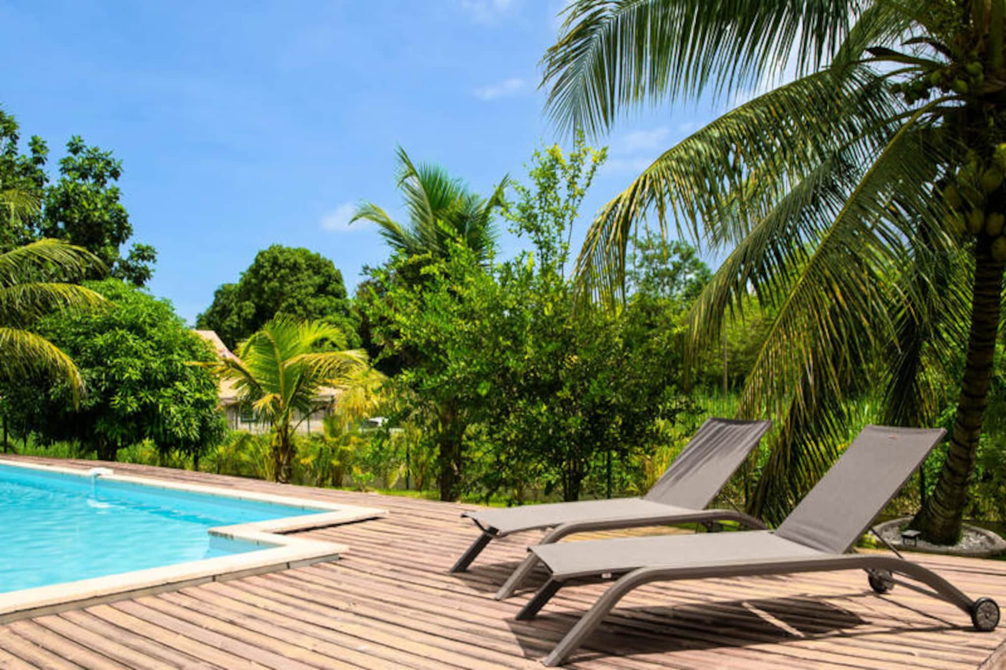 In the heart of Guadeloupe’s lush countryside, Villa Le Maroni offers an idyllic escape where nature’s beauty meets modern comfort. Surrounded by vibrant tropical vegetation and fruit trees like coconut and sugarcane, this spacious single-story villa invites you to unwind in a serene setting. Imagine starting your day with a swim in the large private pool, basking in the Caribbean sun, and enjoying views of the majestic La Soufrière volcano on clear days. Evenings are perfect for stargazing by the pool or savoring a meal prepared in the outdoor kitchen equipped with a gas barbecue and griddle. 
 
 Inside, the villa spans 110 m² and is thoughtfully designed to accommodate up to 6 adults and 4 children. The four air-conditioned bedrooms include three with queen-size beds and one with a bunk bed and pull-out bed, ideal for younger guests. The modern kitchen is a culinary delight, featuring a wine cellar, coffee maker, and even a popcorn machine. Music enthusiasts will adore the piano, adding a touch of charm to your evenings. For family fun, a selection of board games is available, ensuring memorable moments together. 
 
 Villa Le Maroni’s location in Le Lamentin, Basse-Terre, is perfect for exploring Guadeloupe’s treasures. Within a 10-minute drive, you’ll find supermarkets, bakeries, and restaurants. The Route de la Traversée is just 10 minutes away, offering access to lush rainforests and scenic trails. For a day trip, visit the Deshaies Botanical Garden or the stunning Malendure Beach, both less than 40 minutes away. Relax at the nearby Ravine Chaude Thermal Spa, where naturally warm waters provide ultimate rejuvenation. 
 
 With air conditioning, internet access, and hotel-quality cleaning, Villa Le Maroni ensures a seamless and comfortable stay. Enjoy a welcome cocktail upon arrival and let our concierge arrange excursions, car rentals, or local activities tailored to your preferences. Whether you seek relaxation or adventure, this Caribbean retreat promises unforgettable memories.