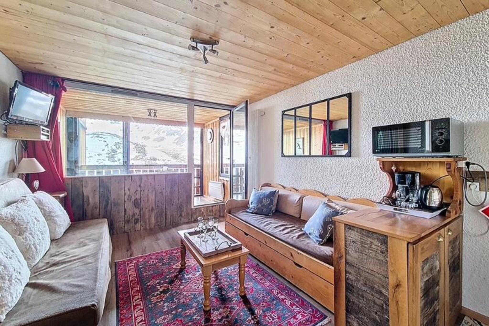 High above the vibrant streets of Val Thorens, this charming studio apartment offers a cozy retreat with breathtaking views of the surrounding alpine landscape. Situated on the 7th floor of the LE SERAC residence, this south-facing gem bathes in natural light, creating a warm and inviting atmosphere for up to four guests. Whether you're here to carve the pristine slopes or simply soak in the mountain serenity, this property promises an unforgettable stay in the heart of the Three Valleys ski domain. \n\nInside, the apartment is thoughtfully designed for comfort and convenience. The living room features a sofa bed for two, an additional sofa, and a television, perfect for unwinding after a day of adventure. The open-plan kitchen is fully equipped with modern appliances, including a 4-burner hob, microwave with grill function, refrigerator, coffee maker, kettle, and toaster, making it easy to prepare hearty meals. A sleeping alcove with bunk beds (one 140 cm and one 90 cm) provides a cozy resting space, while the bathroom includes a bathtub and separate WC for added privacy. With tiled flooring, duvets for bedding, and a ski locker, every detail has been considered to ensure a comfortable stay. \n\nStep outside, and you'll find yourself just moments from the slopes, accessible via the street. The nearby Péclet shopping center offers a variety of restaurants, shops, and essential services like a pharmacy, ensuring you have everything you need at your fingertips. Val Thorens is renowned for its lively après-ski scene, world-class skiing, and stunning mountain vistas, making it a dream destination for winter sports enthusiasts. \n\nWhether you're seeking thrilling descents, cozy evenings, or the simple joy of waking up to the sunlit peaks, this studio apartment is your gateway to the ultimate alpine experience. Book your stay and discover the magic of Val Thorens for yourself.