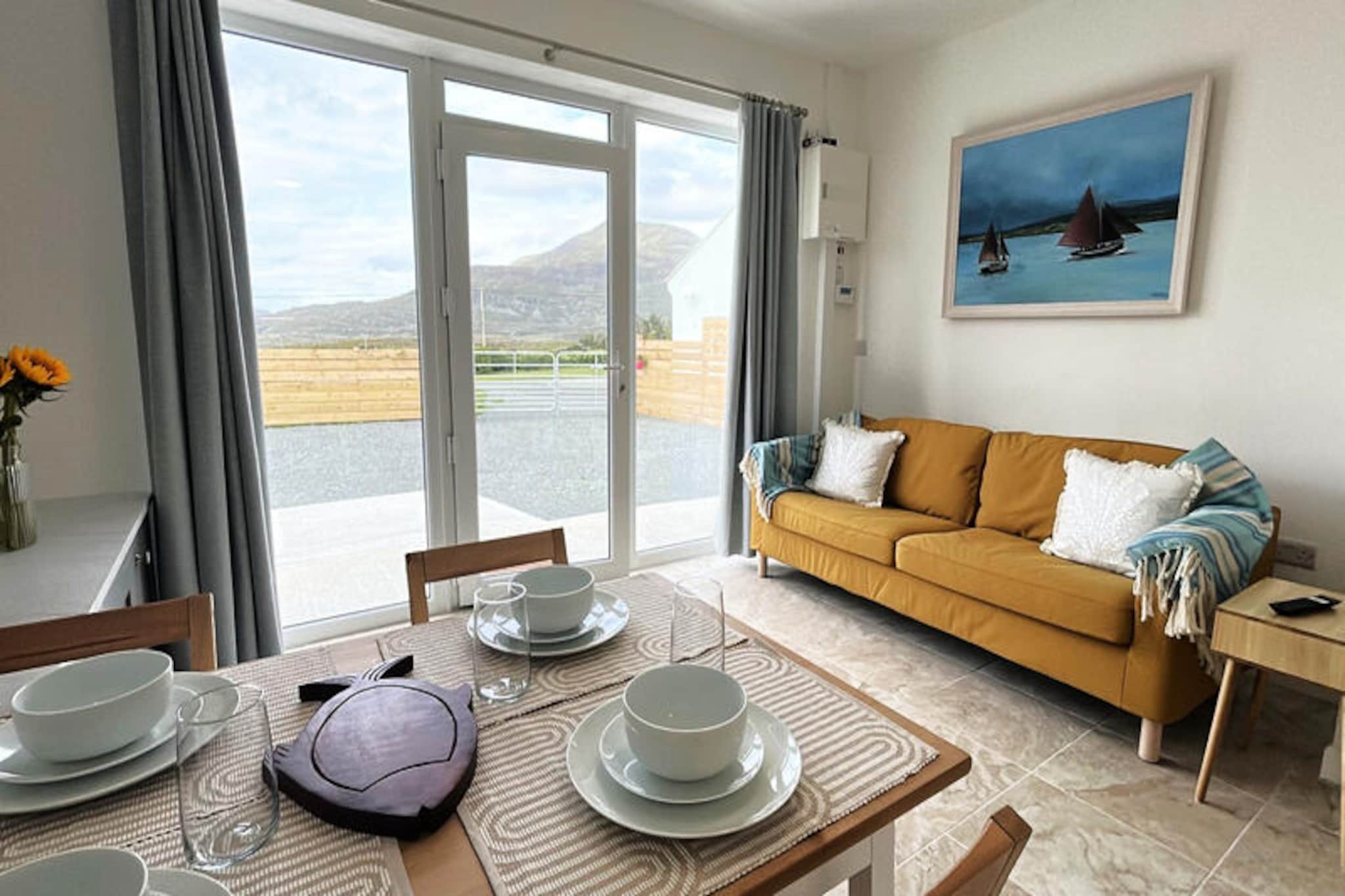 Perched on the rugged coastline of Renvyle, this charming rural cottage offers a serene escape with breathtaking views of the Atlantic Ocean and the majestic Twelve Bens mountains. The tranquil surroundings invite you to unwind and reconnect with nature, while the nearby beaches and countryside provide endless opportunities for exploration. Whether you're seeking a romantic getaway or a peaceful retreat with loved ones, this cozy haven promises unforgettable moments in the heart of Connemara.  
                      The cottage features two comfortable bedrooms, accommodating up to four guests, making it ideal for small families or couples. The thoughtfully designed interior includes a welcoming living space with a television and radio, perfect for relaxing evenings. The American-style kitchen is fully equipped with modern appliances, including a refrigerator, oven, dishwasher, and coffee maker, ensuring you have everything needed to prepare delicious meals. Additional amenities such as Wi-Fi, central heating, and a washing machine provide convenience and comfort throughout your stay. Step outside to the fenced garden, where you can enjoy the fresh coastal air and stunning views.  
                      Just 700 meters away lies Culfin Beach, a hidden gem perfect for seaside strolls and picnics. Glassilaun Beach, renowned for its golden sands and crystal-clear waters, is only 1 kilometer away. Explore the nearby Connemara National Park, just 11 kilometers from the cottage, where hiking trails lead to panoramic vistas. The charming village of Tully Cross, with its traditional pubs and restaurants, is a short drive away, offering a taste of local culture and cuisine. For a day of adventure, visit Clifden, the vibrant capital of Connemara, located 25 kilometers from the property.  
                      Whether you're drawn to the natural beauty of the area or the warm hospitality of the local community, this idyllic cottage is the perfect base for discovering the wonders of Ireland's west coast. Create lasting memories as you immerse yourself in the enchanting landscapes and rich heritage of Connemara.