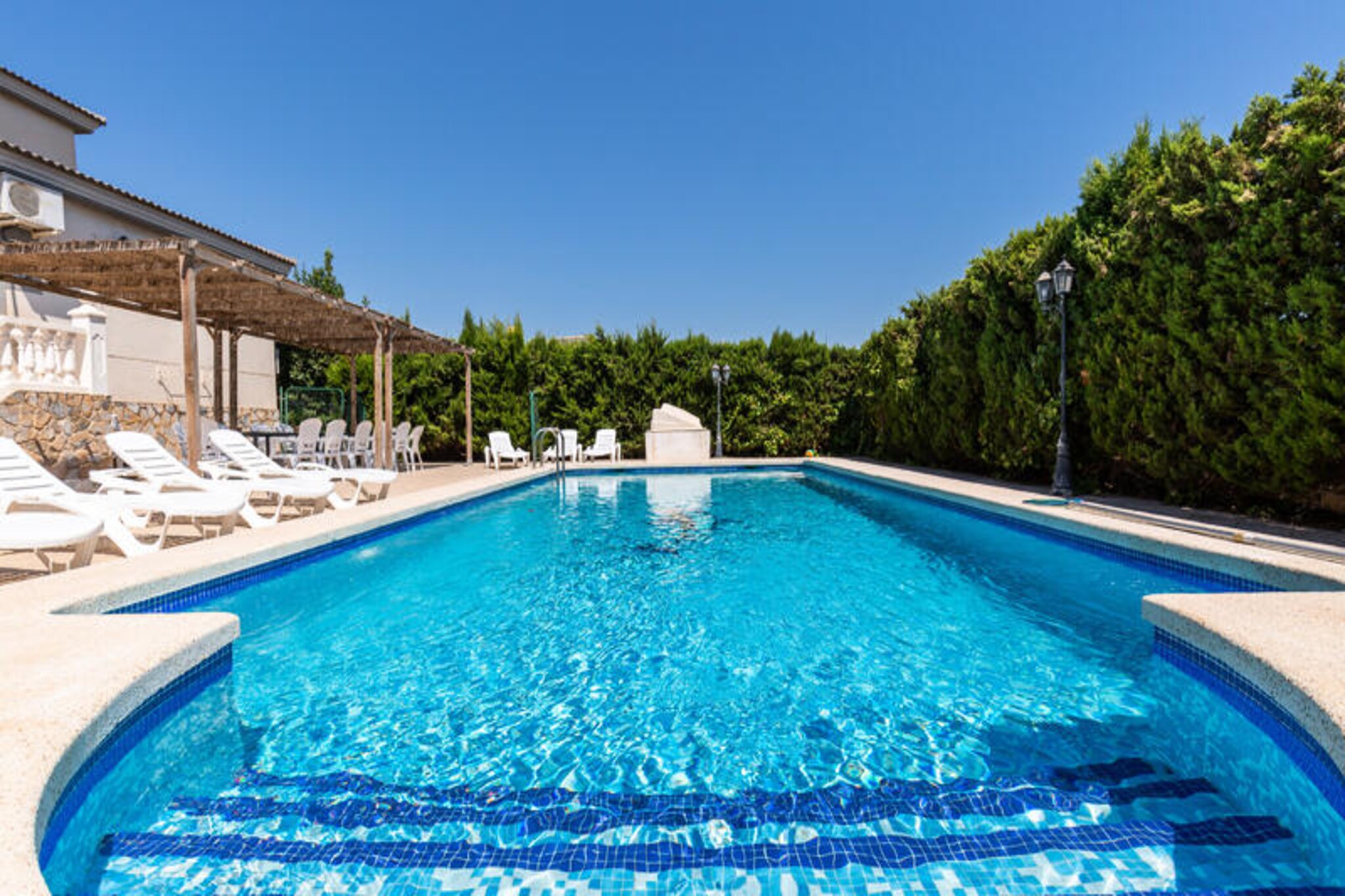 Under the golden Spanish sun, this exclusive villa in Mutxamiel offers a serene escape for those seeking a luxurious retreat near the sparkling beaches of San Juan. With its harmonious blend of contemporary Californian elegance and traditional Mediterranean charm, this property is a haven of tranquility and sophistication, perfect for creating unforgettable memories with family and friends. Surrounded by lush gardens and breathtaking mountain views, the villa invites you to immerse yourself in the beauty of the Costa Blanca. 
 
 Spanning 350 square meters across three levels, the villa boasts 9 beautifully designed bedrooms, accommodating up to 16 guests in absolute comfort. The interiors feature a spacious and tastefully decorated living room, a fully equipped kitchen seamlessly integrated with the dining area, and an additional family room on the lower floor for extra privacy. Each bedroom is a sanctuary of relaxation, offering plush furnishings and elegant details reminiscent of a 5-star hotel. Modern amenities such as air conditioning and heating ensure a comfortable stay year-round. 
 
 Step outside to discover your private oasis. The expansive 1,200-square-meter lot includes a sparkling swimming pool surrounded by verdant gardens, perfect for sunbathing or leisurely afternoons. The terrace and courtyard provide idyllic settings for al fresco dining, while the barbecue area promises delightful evenings under the stars. From the superior balcony, marvel at panoramic mountain views and magical sunsets that will take your breath away. 
 
 Located just minutes from the pristine beaches of San Juan and Mutxamiel, the villa offers the perfect balance of seclusion and accessibility. Nearby, you’ll find a variety of restaurants, leisure activities, and entertainment options to enhance your stay. Whether you’re seeking relaxation, adventure, or a mix of both, this villa is your gateway to an extraordinary holiday on the Costa Blanca.