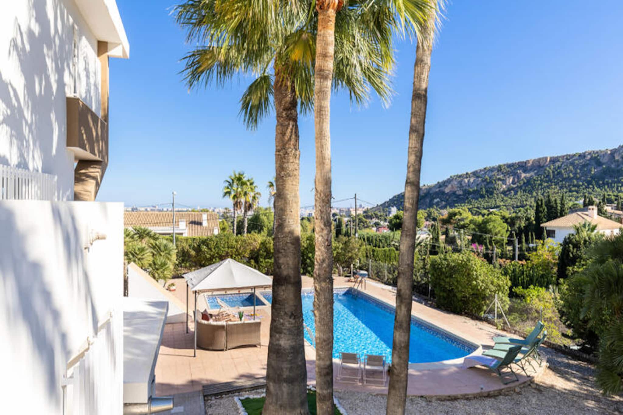 In the vibrant city of Alicante, this Mediterranean-inspired villa offers a serene escape with a touch of urban sophistication. Surrounded by lush greenery and bathed in natural light, this two-story home is a haven for relaxation and entertainment. The property’s design seamlessly blends indoor and outdoor living, with expansive terraces leading to a private swimming pool and a beautifully landscaped garden. Whether you’re lounging in the chill-out area, enjoying a barbecue with mountain views, or sipping a refreshing drink by the pool, every corner of this home invites you to unwind and savor the Spanish sun.
Spanning an impressive 432 square meters on a generous 1800-square-meter plot, the villa features seven spacious bedrooms, three modern bathrooms, and a large living and dining area that comfortably seats up to 16 guests. The fully equipped kitchen is perfect for preparing meals to be enjoyed in the outdoor dining space or the elegant indoor setting. Additional amenities include a private gym, smart TV, Wi-Fi, and parking for up to 10 cars, ensuring a comfortable and luxurious stay for families or groups of friends.
Located just a 5-minute walk from Alicante’s renowned Gran Vía, you’ll find two shopping centers, a variety of restaurants, cafes, and pubs, as well as excellent public transport links to the city center and nearby beaches. Whether you’re exploring the lively streets of Alicante, relaxing by the pool, or enjoying the breathtaking mountain views, this villa offers the perfect balance of tranquility and convenience.
Experience the warmth and charm of Mediterranean living in this exceptional property, where every detail has been designed to create unforgettable memories.