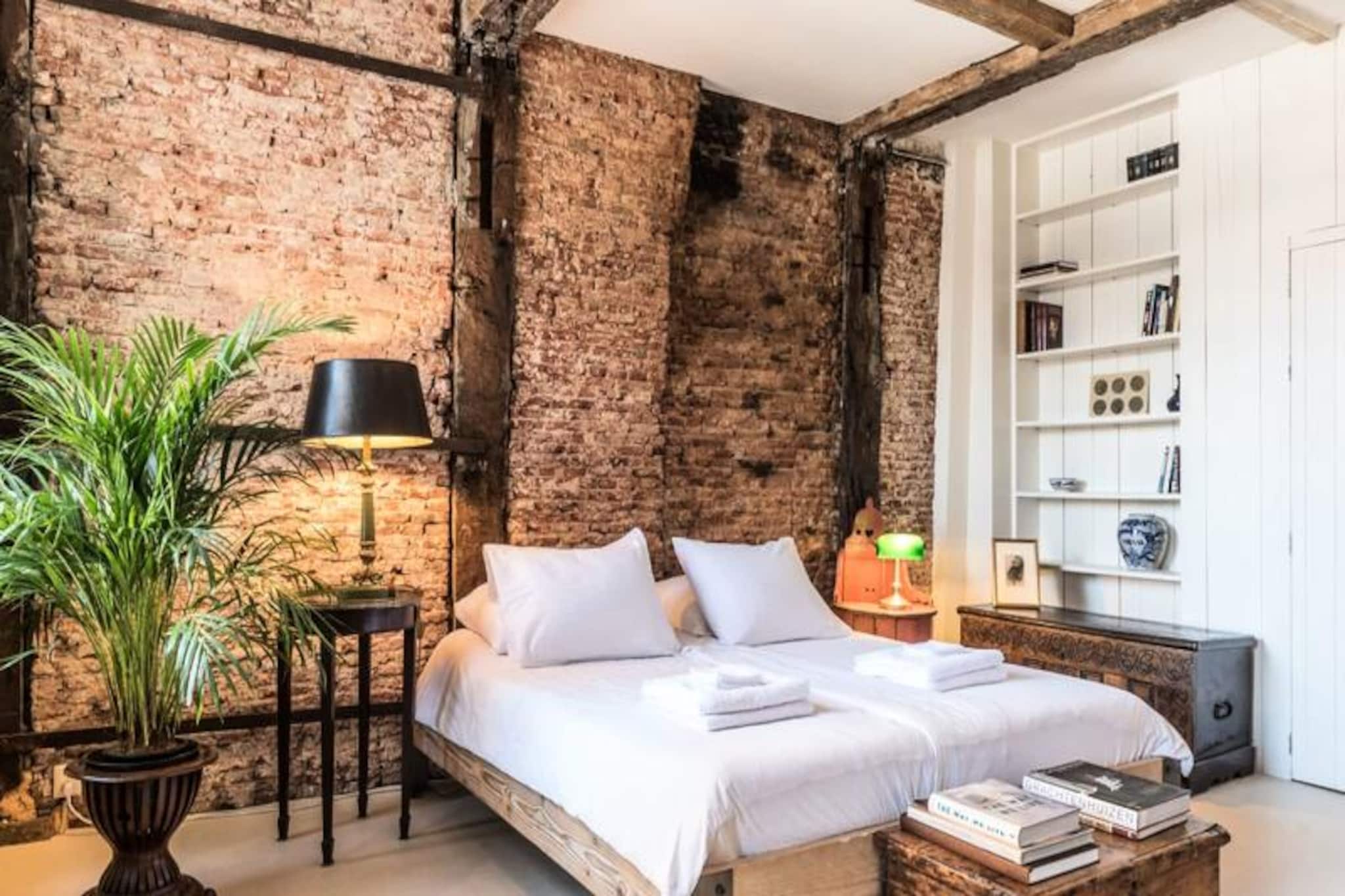 Step into a world of history and charm with this private double room in a canal house dating back to 1608, situated along the iconic Singel canal in Amsterdam’s oldest district. Perfectly positioned in the heart of the city, this unique accommodation offers a blend of historic authenticity and modern comfort, inviting you to experience the magic of Amsterdam from a truly exceptional base. Imagine waking up to the gentle ripples of the canal, surrounded by centuries-old architecture and vibrant city life just outside your window. \n\nThe room, spanning 50 square meters, is thoughtfully designed to provide both comfort and character. Exposed oak beams and an authentic brick wall add a touch of rustic elegance, while the spacious bedroom features a double bed with two latex mattresses for restful nights. Adjacent to the bedroom is your private bathroom, equipped with a shower, sink, and toilet. A cozy sitting area with a sofa, chairs, cable TV, Wi-Fi, and a study desk ensures you have everything you need for relaxation or work. Though there’s no kitchen, the room includes a coffee machine, kettle, small refrigerator, and dining essentials for light meals and beverages. \n\nStep outside and find yourself immersed in Amsterdam’s vibrant culture. Central Station is just a 5-minute walk away, connecting you to the city’s treasures and beyond. Explore nearby attractions like the Anne Frank House, Rijksmuseum, and Van Gogh Museum, or stroll through Westerpark for a moment of tranquility. The neighborhood boasts organic grocery stores, bike rentals, cinemas, and an array of restaurants offering diverse cuisines. \n\nWhether you’re here for the canals, museums, or simply to soak in the city’s unique atmosphere, this historic canal house offers a one-of-a-kind stay. Let the charm of Amsterdam’s oldest quarter become the backdrop to your unforgettable journey.