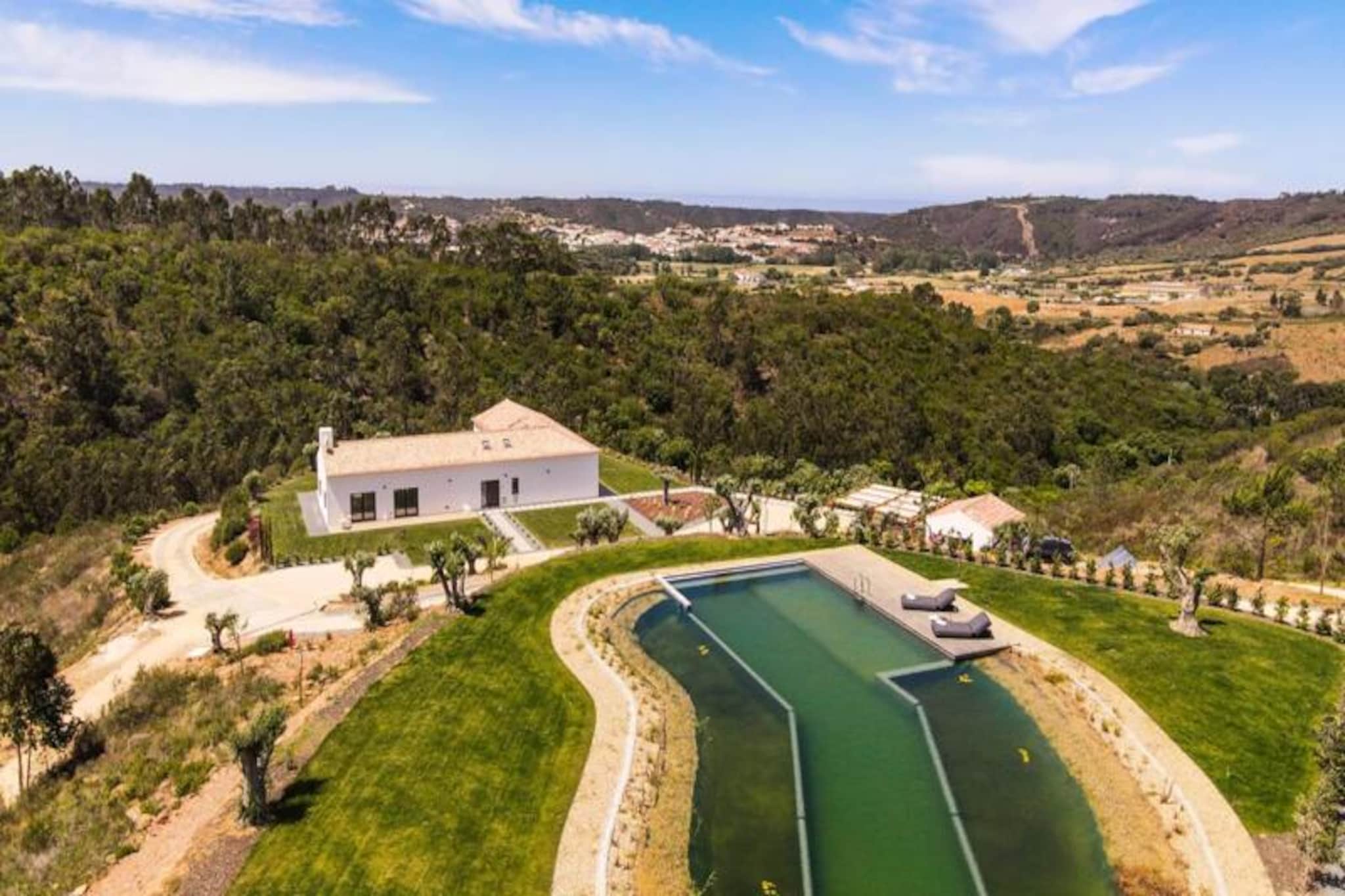 Surrounded by the serene beauty of Portugal’s Alentejo region, Vale de Agua offers an exclusive retreat for those seeking tranquility, modern comfort, and breathtaking natural landscapes. This private estate is a haven for relaxation, set amidst 55 hectares of pristine land featuring a natural pond, a private lake, and lush pine and oak forests. Whether you’re looking to unwind or explore, this property provides the perfect balance of seclusion and adventure. 
 
 The villa’s design harmoniously blends traditional Alentejo architecture with contemporary elegance. Inside, you’ll find a spacious and light-filled 300 m² home with four double bedrooms, including three en suite bathrooms, a 90 m² open-plan living, dining, and kitchen area, and additional spaces like a cozy TV lounge and a 50 m² office. Large windows frame the stunning views, while the minimalist interiors, wooden floors, and modern furnishings create a calming atmosphere. Step outside to enjoy the landscaped garden, a natural swimming pool with a sun terrace, and a partially covered patio perfect for al fresco dining. 
 
 Located just 1 km from the Costa Vicentina Natural Park and 5 km from the Atlantic Ocean, this estate is a gateway to some of Portugal’s most spectacular beaches. From the surfer’s paradise of Arrifana to the golden sands of Odeceixe, the coastline offers endless opportunities for adventure. The charming town of Aljezur is nearby, and the vibrant city of Lagos is just a 35-minute drive away. 
 
 Whether you’re drawn by the allure of uncrowded beaches, the charm of Alentejo’s countryside, or the comfort of a beautifully designed home, Vale de Agua promises an unforgettable escape. Perfect for families, couples, or friends, this property invites you to experience the best of Portugal in style and serenity.