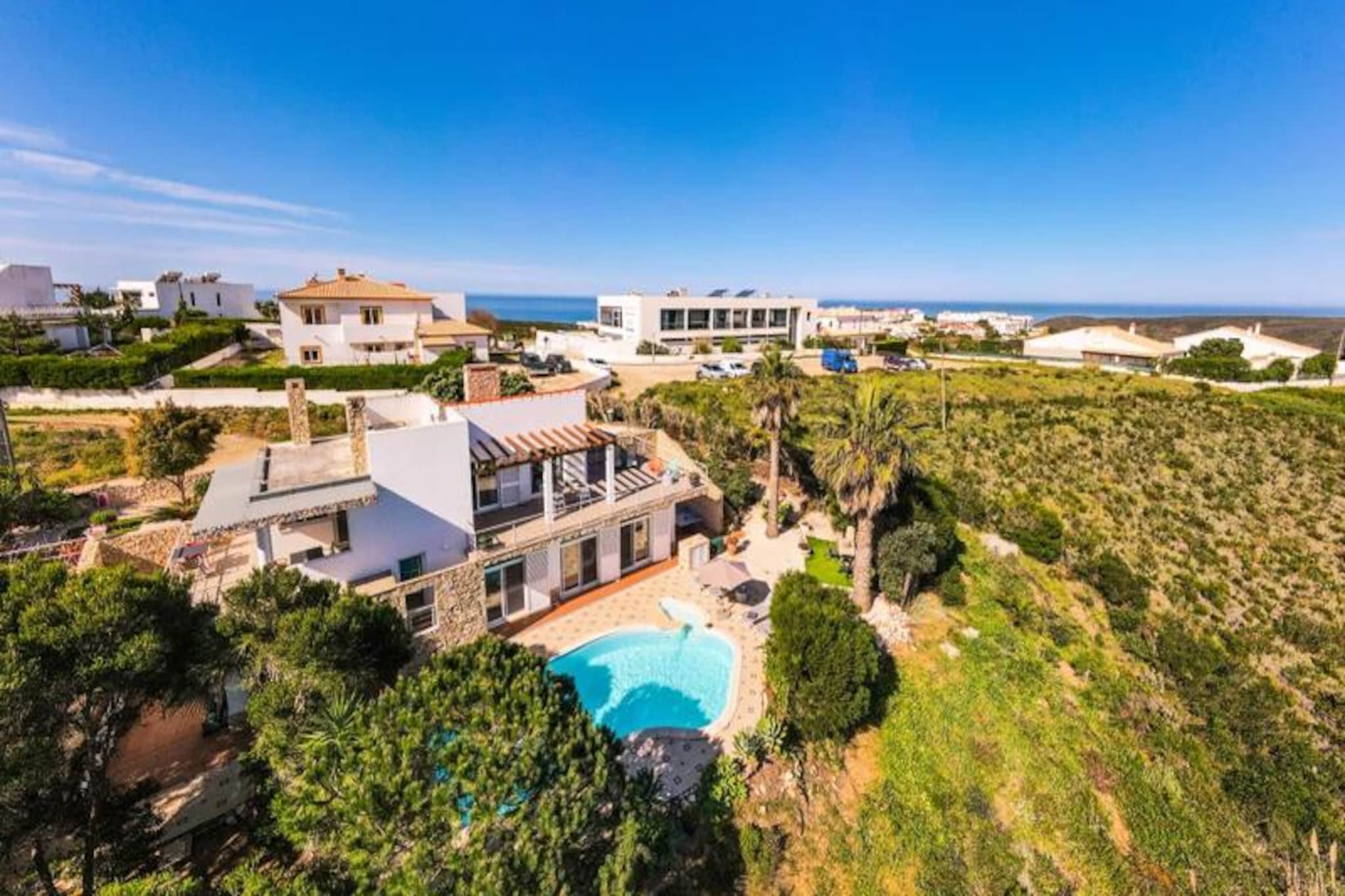 Imagine waking up to the soothing sound of ocean waves and the scent of fresh sea air, just a short stroll from the stunning Praia da Arrifana. Nestled in the heart of the Costa Vicentina Natural Park, this magnificent four-bedroom villa offers the perfect blend of modern comfort and natural beauty. Whether you’re seeking a serene retreat or an adventure-filled getaway, this property is your gateway to the unspoiled charm of Portugal’s western Algarve. 
 
 This two-story villa boasts a contemporary design with abundant natural light and a welcoming atmosphere. The upper floor features a spacious living and dining area with high wooden ceilings, a cozy fireplace, and large windows that frame breathtaking views of the valley and distant sea. The fully equipped kitchen, complete with a barbecue area, invites you to savor the flavors of the Algarve. Downstairs, four generously sized bedrooms with built-in wardrobes provide direct access to the lush garden and saltwater pool, ensuring a restful stay for up to eight guests. Modern amenities like high-speed internet, Apple TV, and central heating (available at an additional cost) ensure year-round comfort.
 
 Step outside to discover your private oasis. The expansive garden, complete with a ping-pong table, sun loungers, and a sparkling pool, is perfect for relaxation or family fun. The villa’s location is a dream for outdoor enthusiasts, with the Rota Vicentina hiking trails passing right by the property and world-class surf spots just minutes away. Explore the charming town of Aljezur, only 6 km away, or take a day trip to vibrant Algarve destinations like Lagos and Portimão. 
 
 Whether you’re drawn by the allure of the waves, the tranquility of nature, or the vibrant local culture, this villa promises an unforgettable escape. Welcome to your home away from home, where every detail has been thoughtfully designed to create lasting memories.