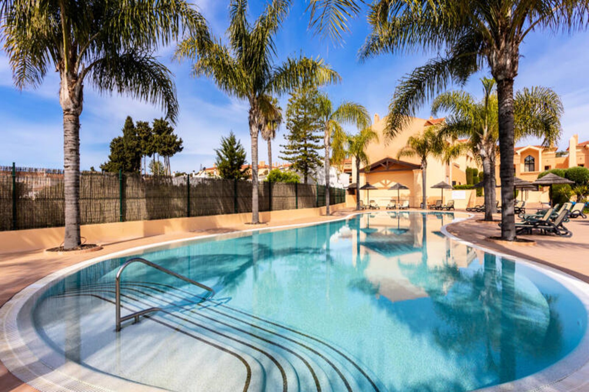 Awaken your senses in the charming seaside village of Praia da Luz, where this luxurious apartment offers a tranquil retreat surrounded by the azure waters of the Atlantic and the dramatic Rocha Negra cliffs. The Algarve’s natural beauty unfolds right outside your doorstep, creating the perfect backdrop for a memorable holiday. Whether you’re seeking relaxation or adventure, this destination has it all. \n\nStep into a world of comfort and sophistication within this thoughtfully designed apartment. High-quality finishes and modern amenities ensure a seamless stay, including underfloor heating, air conditioning, satellite TV, and a fully equipped kitchen with Siemens appliances. The spacious layout accommodates up to four adults and two children, making it ideal for families or couples. Situated in the Baía da Luz complex, the property reflects a blend of Arabic and Roman architectural influences, creating a village-like ambiance. Guests can enjoy two large swimming pools, a heated children’s pool, a playground, and sports courts, all set amidst beautifully landscaped gardens. \n\nPraia da Luz is a gem on the Algarve coast, offering a sheltered bay perfect for family beach days and water sports like surfing. The vibrant town of Lagos, just a 10-minute drive away, boasts a historic center, a lively marina, and breathtaking cliffs best explored by boat or kayak. Nearby, you’ll find charming seaside towns and pristine beaches, making this an excellent base for exploring the region. Golf enthusiasts will appreciate the proximity to four courses within a short drive. \n\nWhether you’re savoring Italian cuisine at the on-site Alloro restaurant, lounging by the heated pool, or exploring the Algarve’s stunning coastline, this apartment promises an unforgettable escape. With its blend of luxury, comfort, and prime location, your perfect holiday awaits.