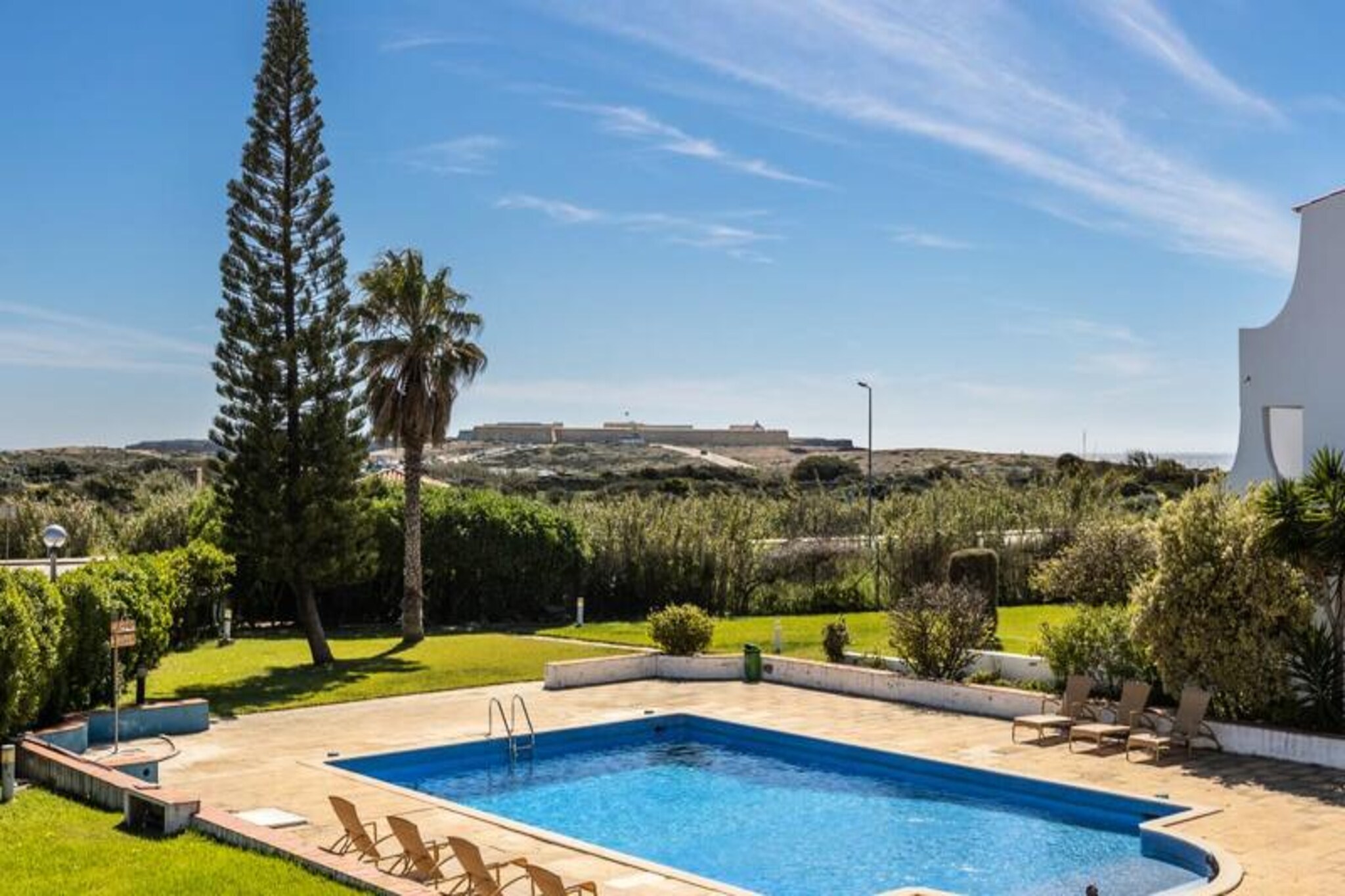 In the serene coastal town of Sagres, where golden cliffs meet the azure Atlantic, the Julio Pomar apartment offers a luxurious retreat for families and groups seeking a memorable escape. Imagine waking up to the sound of waves and stepping out onto your private balcony to take in breathtaking views of the sea and the iconic Sagres Fortress. This is more than just a stay; it’s an invitation to immerse yourself in the beauty and tranquility of Portugal’s Algarve region. 
 
 Spacious and bright, the apartment comfortably accommodates up to seven guests with three well-appointed bedrooms and two modern bathrooms. The open-plan living area, bathed in natural light, leads to expansive balconies that are perfect for morning coffees or sunset gatherings. A fully equipped kitchen, complete with a Delta Q coffee machine, ensures you have everything needed for a comfortable and self-catered stay. Reversible air conditioning in every room, Wi-Fi, and a television add to the convenience, making it a home away from home. 
 
 Step outside, and you’ll find a shared swimming pool, lush garden, and tennis court, offering relaxation and recreation just steps from your door. For the adventurous, Sagres is a haven for surfing, windsurfing, paddleboarding, and even dolphin-watching excursions. The apartment’s prime location places you just 200 meters from pristine surf beaches and within walking distance of supermarkets, surf shops, restaurants, and bars. 
 
 Whether you’re exploring the rugged coastline, savoring fresh seafood, or simply unwinding in the peaceful surroundings, the Julio Pomar apartment is your gateway to an unforgettable Algarve experience. Book your stay today and create lasting memories in this idyllic seaside haven.