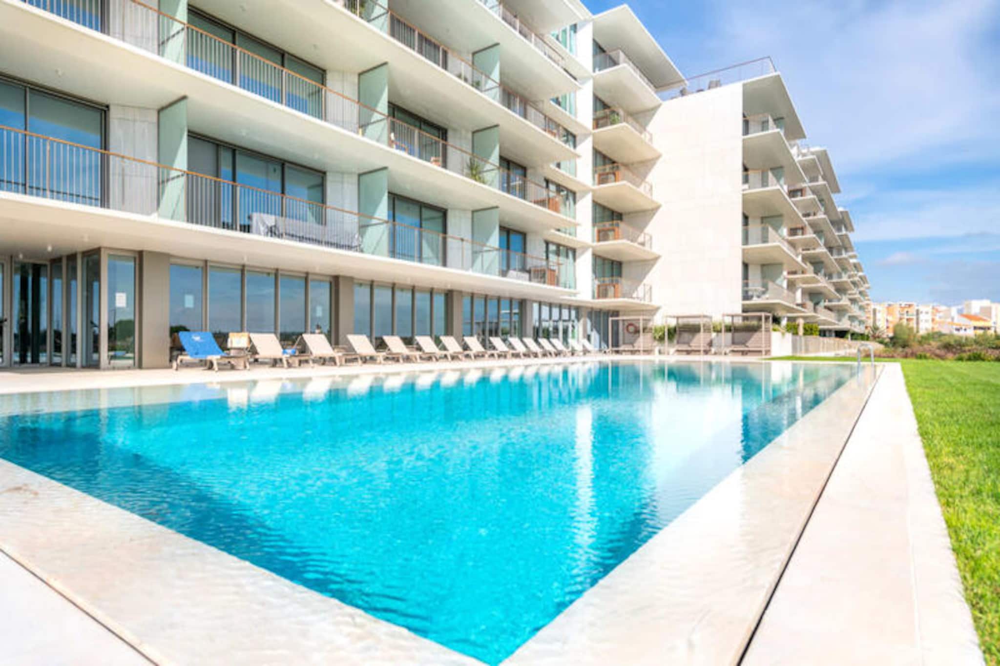 Wake up to the gentle sound of waves and the golden glow of the Algarve sun in this exquisite one-bedroom apartment at the Bayline complex in Armação de Pêra. Situated just 100 meters from the beach, this retreat combines modern luxury with the timeless charm of Portugal’s southern coastline, offering an unparalleled seaside escape. Whether you’re sipping your morning coffee on the private east-facing balcony or strolling along the sandy shores, every moment here is designed to inspire relaxation and joy. 
 
 Inside, the apartment welcomes you with a bright, open-plan living space, complete with a fully equipped kitchen featuring high-end appliances and elegant finishes. The master bedroom, furnished with a plush queen-size bed, ensures restful nights, while the stylish bathroom provides both privacy and convenience. Air conditioning in all rooms guarantees comfort year-round, and electric blinds add a touch of modern sophistication. 
 
 As a guest of the prestigious Bayline complex, enjoy exclusive access to exceptional amenities, including indoor and outdoor swimming pools, a rejuvenating spa, and a state-of-the-art gym. Private parking is available, and the complex is thoughtfully designed to ensure a peaceful and secure environment for all visitors. 
 
 Step outside and discover the vibrant town center just 500 meters away, where you can indulge in fresh seafood at local restaurants, explore charming boutiques, or soak in the region’s rich history at landmarks like the Forte de Santo António. For adventure seekers, nearby attractions such as Zoomarine and the stunning sea caves of Praia da Senhora da Rocha promise unforgettable experiences. Whether you’re here to unwind, explore, or simply bask in the beauty of the Algarve, this apartment offers the perfect base for your dream getaway.