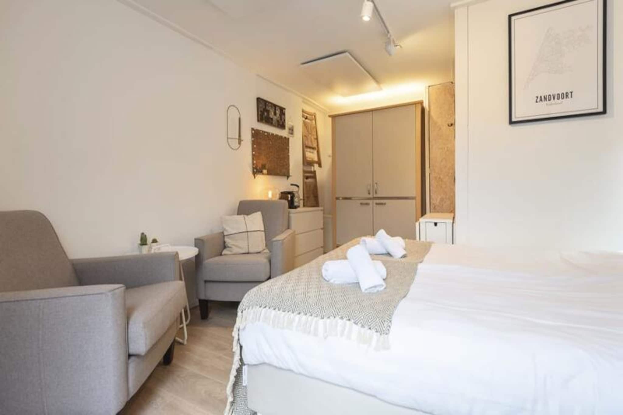 Step into a serene coastal retreat in the heart of Zandvoort, where the charm of seaside living meets modern comfort. This stylish studio apartment, bathed in soothing white and sand tones, offers a tranquil escape just moments from the golden shores of the North Sea. Whether you're seeking a peaceful getaway or an active beach holiday, this property provides the perfect balance of relaxation and convenience. With its private entrance and cozy terrace, you can enjoy quiet mornings with a cup of coffee or unwind after a day of exploring the vibrant surroundings. \n\nInside, the 19 m² studio is thoughtfully designed for one or two travelers. A plush queen-size bed invites restful nights, while a pair of comfortable armchairs and a dining table create a welcoming space to relax or plan your adventures. The modern bathroom features a shower, sink, and toilet, and the kitchenette is equipped with a refrigerator and microwave for light meal preparation. Air conditioning and an electric fan ensure a pleasant atmosphere year-round, while Wi-Fi keeps you connected throughout your stay. \n\nLocated on a peaceful side street in Zandvoort's historic center, the studio is just steps away from the beach, lively promenade, and a variety of beach clubs, bars, and restaurants. Nature enthusiasts will love the proximity to the Waterleidingduinen and Kennemerduinen national parks, offering scenic hiking and cycling trails. For thrill-seekers, Circuit Park Zandvoort is nearby, hosting motor racing events and activities. \n\nWith easy access to Amsterdam and Haarlem via public transport, you can effortlessly combine a city break with a relaxing seaside escape. Whether you're here to soak up the sun, explore nature, or experience the vibrant local culture, this studio apartment is your ideal base for an unforgettable Zandvoort adventure.