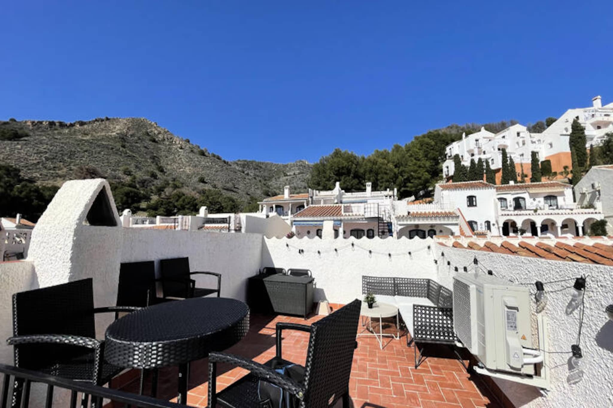 In the picturesque San Juan de Capistrano district of Nerja, this charming two-bedroom apartment invites you to experience the essence of Andalusian living. Surrounded by the beauty of the Sierra Tejeda-Almijara Natural Park and designed as a traditional white Mediterranean village, the area exudes tranquility and charm, making it the perfect retreat for families or couples seeking a serene getaway. With its flower-filled streets, wide avenues, and lush green spaces, every corner of this residential area offers a sense of timeless beauty and relaxation. 

The apartment comfortably accommodates up to four guests, with the option for two small children to sleep on a cot. Inside, you’ll find two cozy bedrooms, a bright living/dining area with an open-plan kitchen, and a bathroom with a modern shower. The terrace offers stunning views, while the private solarium provides a sun-soaked space to unwind. Equipped with a ceramic hob, refrigerator, microwave, oven, toaster, coffee maker, and all necessary utensils, the kitchen ensures you can prepare delicious meals with ease. Additional comforts include air conditioning/heating, free Wi-Fi, and a TV with Spanish and international channels.

Guests can enjoy access to a large communal swimming pool with a separate children’s pool, surrounded by a spacious green area where sun loungers are available for rent. Poolside snack bars offer refreshments, and a nearby supermarket and restaurant cater to your daily needs. The property is ideally located just 2 km from the sandy shores of Playa Burriana and the vibrant center of Nerja, with its array of restaurants, shops, and cultural attractions. A convenient city bus service runs every 45 minutes, connecting you to the town and its renowned beaches.

Whether you’re exploring the natural wonders of the nearby Maro-Cerro Gordo Cliffs, strolling along the Chillar River, or simply soaking up the Andalusian sun, this apartment provides a perfect base for unforgettable memories in one of Spain’s most enchanting coastal destinations.