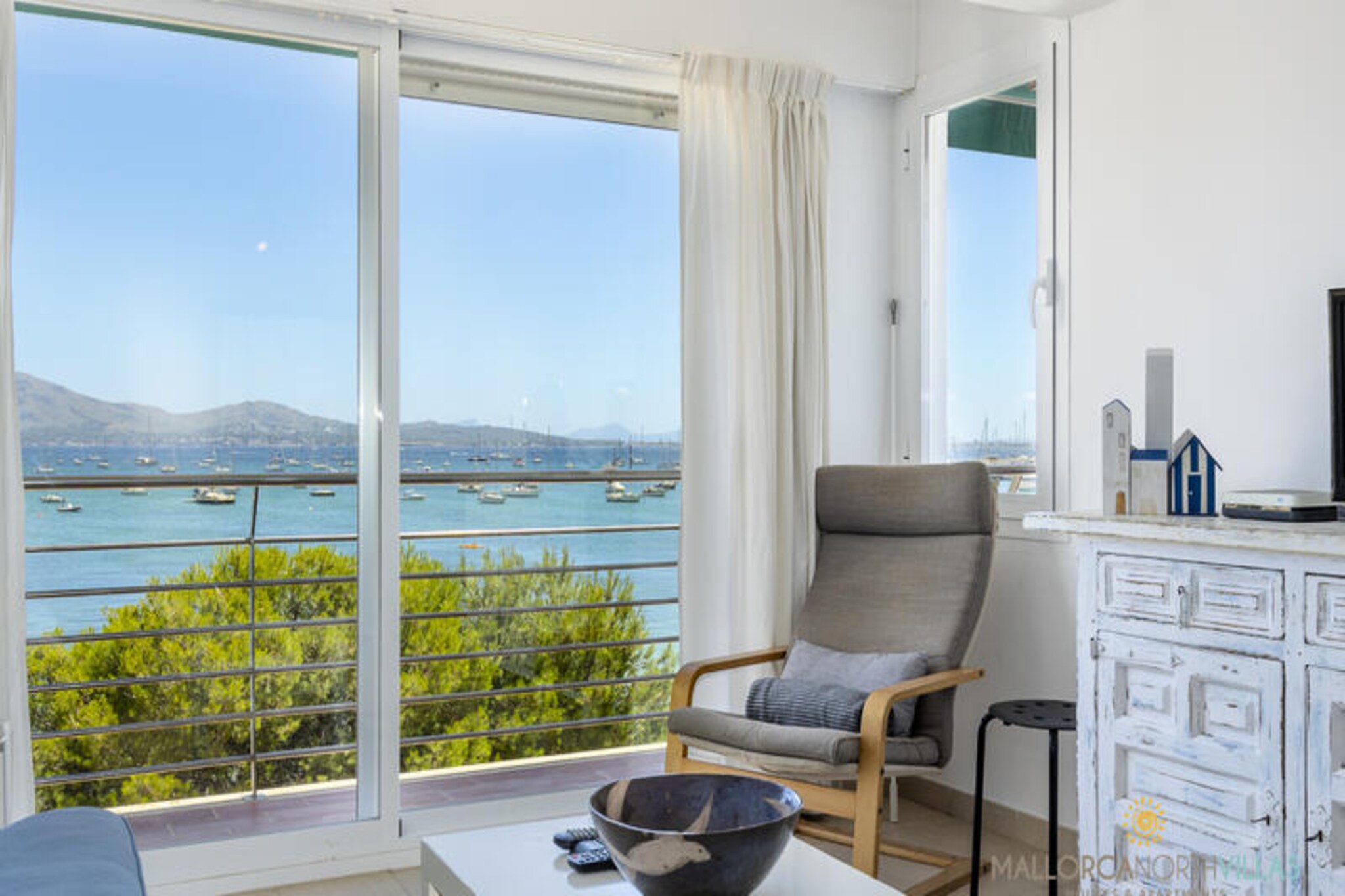 Awaken to the gentle sound of waves and the shimmering blue of the Mediterranean in this charming seaside apartment in Port de Pollensa. Perfectly situated near the iconic Pine Walk, this holiday retreat offers an idyllic escape for families or couples seeking tranquility and breathtaking views. The apartment’s prime location in a peaceful pedestrian area ensures a serene atmosphere while keeping you just steps away from the vibrant heart of this picturesque Mallorcan town.
Inside, the 69 m² apartment is thoughtfully designed to combine comfort and style. It accommodates up to four guests with two cozy bedrooms: a master bedroom featuring a double bed and stunning sea views, and a second interior bedroom with two single beds. The spacious living room, bathed in natural light from large bay windows, opens up to panoramic views of Pollensa Bay, creating a perfect setting for relaxation or shared meals. A fully equipped kitchen, free Wi-Fi, TV, and air conditioning in key areas ensure a comfortable stay year-round.
Step outside and immerse yourself in the charm of Port de Pollensa. From the apartment, you’re just a short stroll to local shops, inviting cafes, supermarkets, and a variety of restaurants offering delicious Mediterranean cuisine. The Pine Walk, with its scenic coastal path lined by pine trees, is a must for leisurely walks or morning jogs. And with the beach right at your doorstep, sun-soaked days and refreshing swims are effortlessly within reach.
Whether you’re planning a romantic getaway or a family holiday, this beachfront haven offers the perfect blend of convenience, natural beauty, and Mallorcan charm. Let the soothing rhythm of the sea and the allure of Pollensa Bay create unforgettable memories for your Mediterranean escape.
