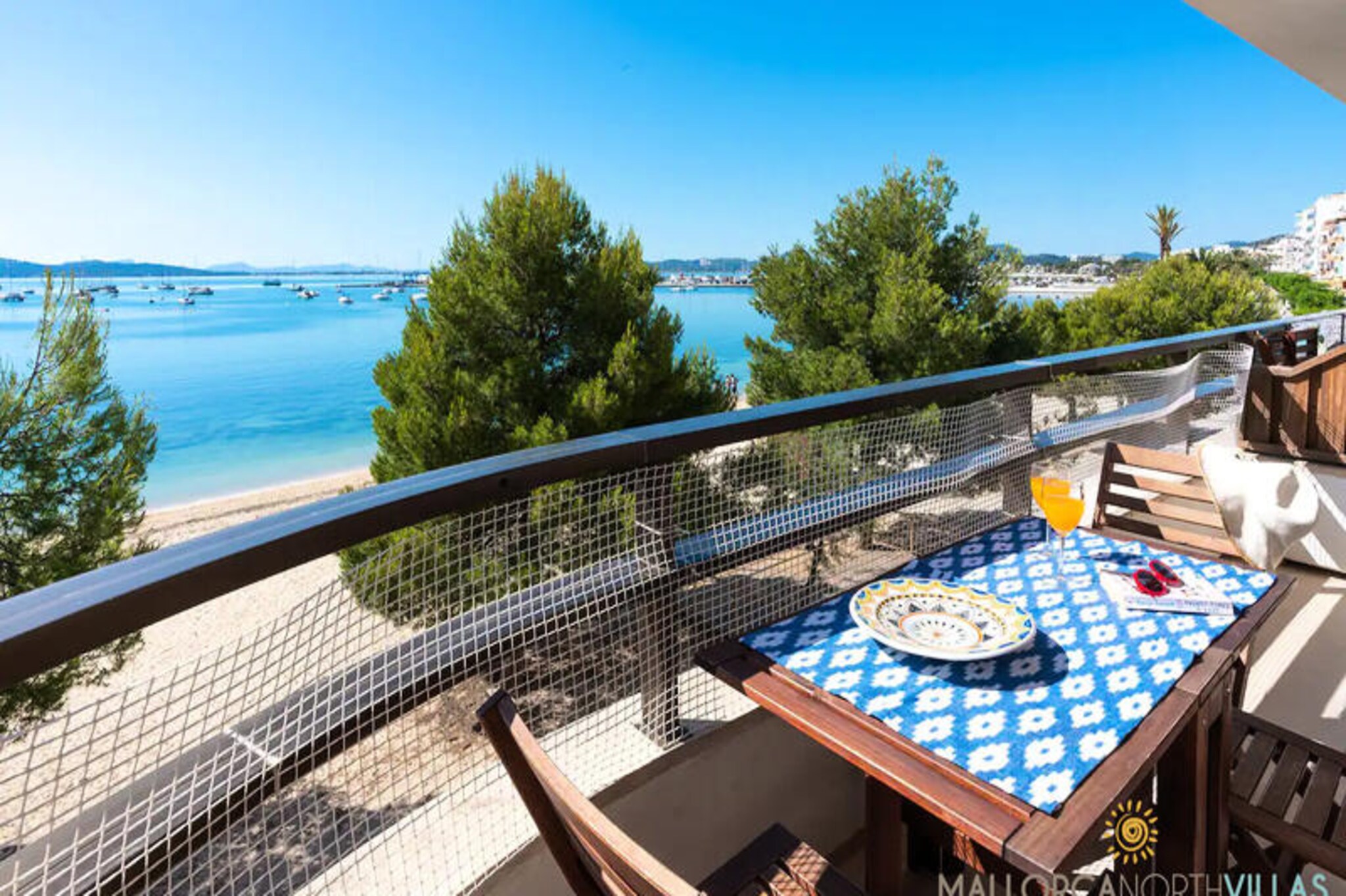 Imagine waking up to the gentle sound of waves and the golden hues of the Mediterranean sunrise. This charming beachfront apartment in Port de Pollença offers a serene escape with breathtaking views of the sea and the bustling marina. Located on the iconic Pinewalk promenade, it’s the perfect spot to immerse yourself in the tranquil beauty of Mallorca while enjoying the vibrant local atmosphere. \n\nThe 85 m² apartment is thoughtfully designed for comfort and convenience, accommodating up to four guests. It features two cozy bedrooms with ceiling fans, a modern bathroom with a shower, and a bright living/dining area that opens onto a terrace with stunning sea views. The fully equipped kitchen is perfect for preparing meals to enjoy al fresco as you soak in the coastal scenery. With air conditioning in the living spaces, Wi-Fi, and satellite TV, every detail has been considered to make your stay as relaxing as possible.\n\nStep outside, and you’ll find yourself in the heart of a charming neighborhood filled with life. Supermarkets, delightful restaurants, and inviting bars are all within walking distance, making it easy to explore the local flavors and culture. Whether you’re strolling along the Pinewalk, lounging on the sandy beach, or simply enjoying the view from your terrace, this apartment offers an unbeatable location for a car-free holiday.\n\nPerfect for couples or small families, this beachfront retreat combines the best of relaxation and convenience. Let the beauty of Port de Pollença captivate you, and create unforgettable memories in this idyllic Mediterranean haven.