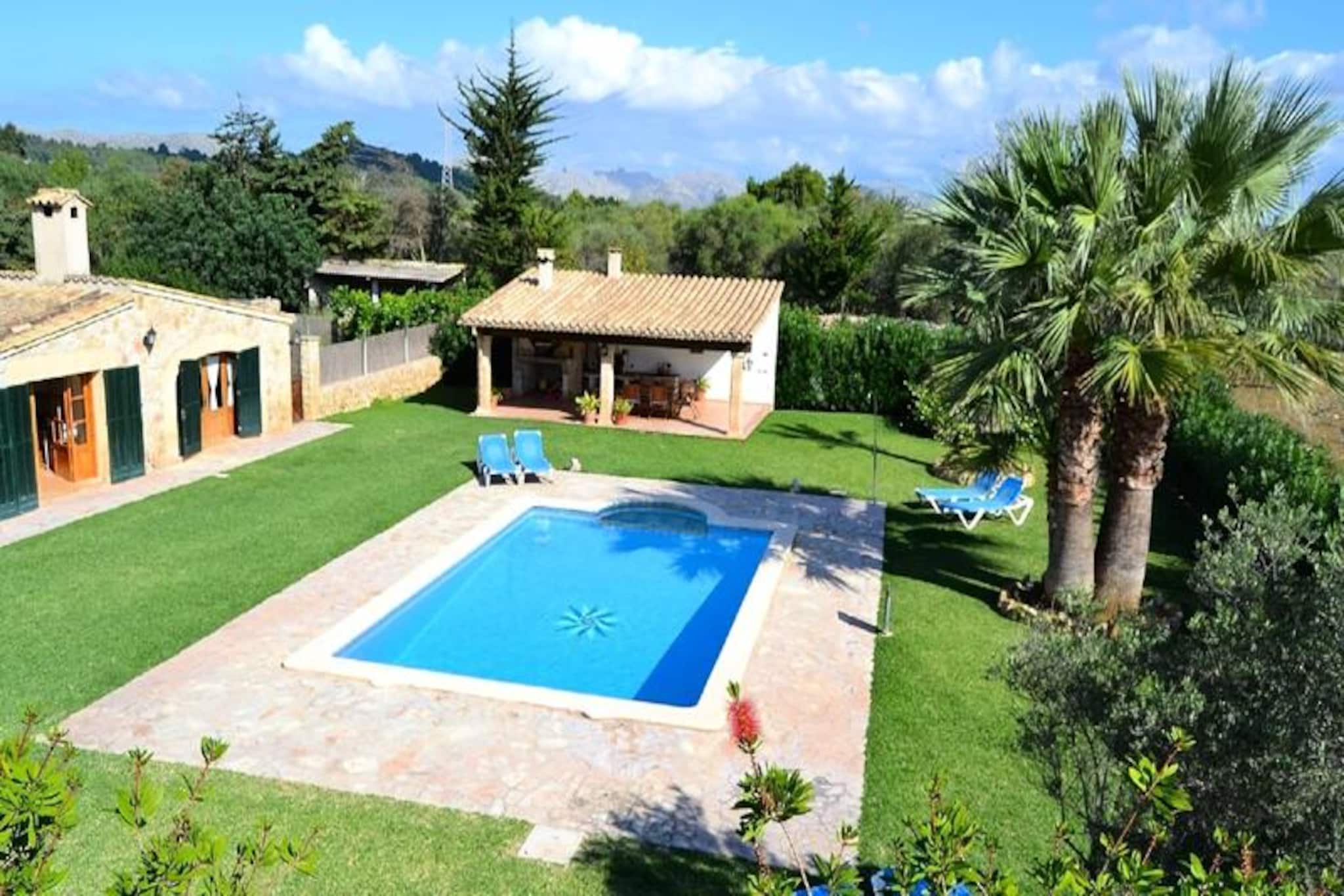 In the heart of Mallorca’s serene countryside, this spacious villa invites you to experience a perfect blend of relaxation and Mediterranean charm. Surrounded by lush greenery and just a short drive from Pollensa’s historic streets, the property offers a tranquil retreat for families and friends seeking a memorable island escape. Imagine waking up to the gentle sound of birdsong, enjoying breakfast in the shaded garden, and spending sun-drenched afternoons by the sparkling pool. This is where cherished holiday memories are made. \n\nThe villa spans 130 m² and comfortably accommodates up to six guests. With three well-appointed bedrooms, including a master suite with a double bed and two twin rooms, it’s ideal for both families and groups. Two modern bathrooms with showers ensure convenience for all. The living area features a spacious dining table, perfect for gathering over meals, while the fully equipped kitchen makes preparing local delicacies a breeze. Air conditioning throughout the house ensures comfort during warmer days. Step outside to discover the charming garden with a covered barbecue area, ideal for evening feasts, and a large swimming pool surrounded by sun loungers for ultimate relaxation. \n\nPollensa’s vibrant town center is just a short drive away, offering cobbled streets, a lively market, and authentic Mallorcan cuisine. Whether you’re exploring the nearby beaches, hiking in the Tramuntana mountains, or simply soaking up the island’s natural beauty, this villa provides the perfect base for your adventures. \n\nChoose this property for its blend of comfort, location, and charm. Whether you’re seeking peaceful days by the pool or cultural exploration in Pollensa, this villa promises an unforgettable Mallorcan experience.