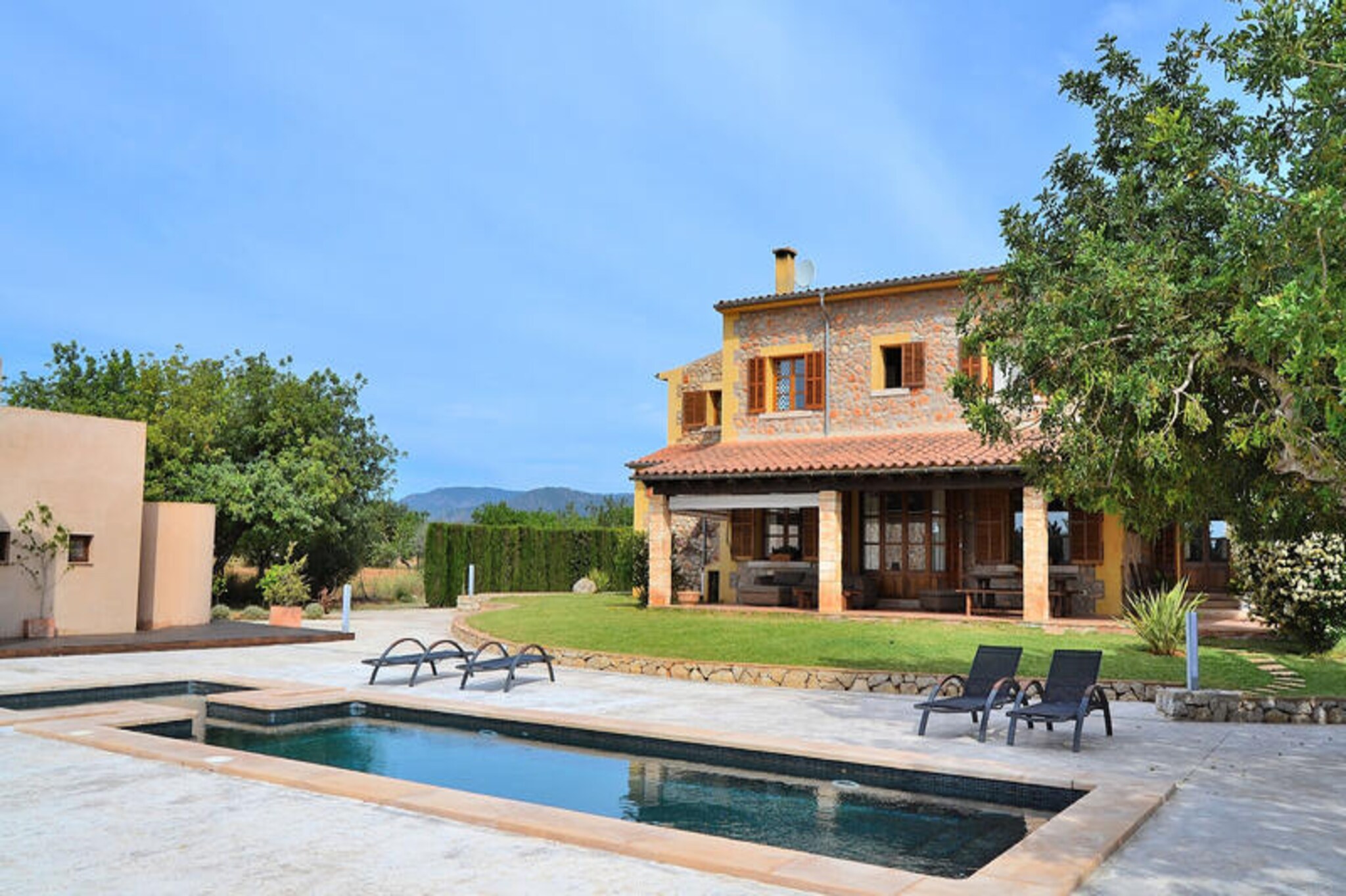 Surrounded by the rolling vineyards of Binissalem, this elegant Mallorcan villa invites you to experience the perfect blend of luxury and tranquility. Step into a world where sophisticated design meets the charm of the Mediterranean countryside, offering a serene retreat for families and friends alike. With its expansive spaces and thoughtful details, this villa is a haven for relaxation and unforgettable moments. \n\nSpanning two floors and over 450 square meters, the villa boasts a spacious living room that flows seamlessly into a dining area and a fully equipped kitchen. The ground floor also features a bedroom with two single beds and a guest toilet for added convenience. Upstairs, the master suite with an en-suite bathroom provides a private sanctuary, while two additional double bedrooms and a full bathroom with a bathtub ensure comfort for all. Every corner of the villa reflects meticulous attention to detail, creating an atmosphere of refined elegance. \n\nStep outside to discover a lush garden complete with a large swimming pool, sun loungers, a ping-pong table, and a barbecue area. Families will appreciate the dedicated children’s play zone, while the outdoor shower and toilet add practicality to this idyllic setting. Whether you’re enjoying a leisurely swim, dining al fresco, or simply soaking up the Mallorcan sun, the outdoor space is designed for relaxation and connection. \n\nLocated in the heart of Binissalem, renowned for its exquisite wines and traditional Mallorcan architecture, the villa offers easy access to local wineries, charming village streets, and breathtaking landscapes. Whether you’re exploring the island’s culinary delights or savoring a glass of local wine, this villa is your gateway to the authentic essence of Mallorca.