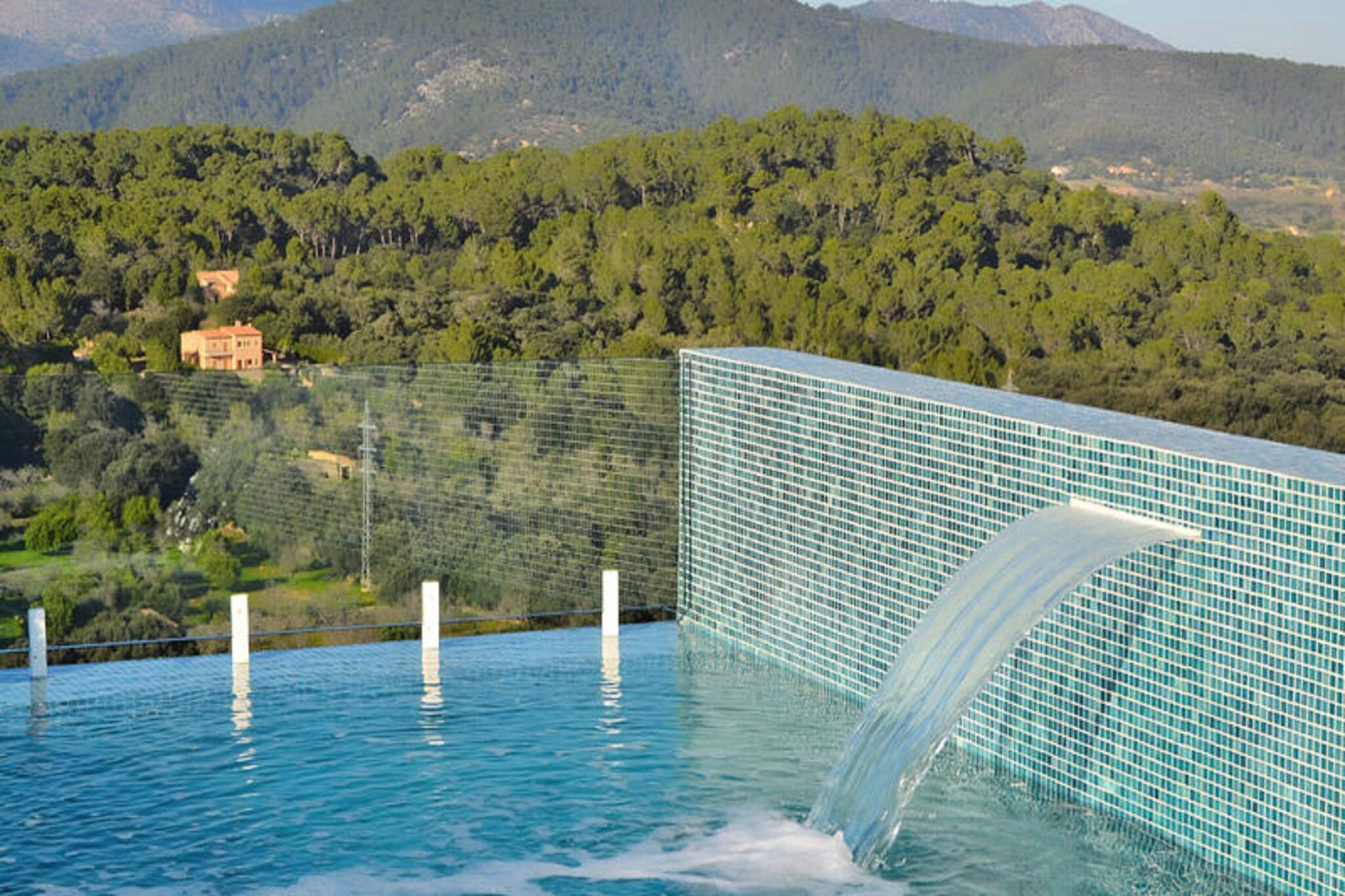 In the serene village of Búger, where the essence of Mallorca’s rural charm meets modern luxury, Villa Montblau stands as a true masterpiece. This recently renovated villa offers a seamless blend of contemporary design and traditional Mediterranean elegance, inviting you to indulge in an unforgettable escape. From its elevated position, the villa boasts panoramic views of the surrounding mountains and lush landscapes, creating an atmosphere of tranquility and exclusivity. Whether you’re soaking in the rooftop jacuzzi or enjoying the refreshing pool, every moment here feels like a retreat into paradise. \n\nSpanning 400 square meters, Villa Montblau features four spacious bedrooms, each designed for ultimate comfort, and five luxurious bathrooms, four of which are en suite. The open-plan layout is adorned with bespoke finishes, including a gourmet kitchen equipped with professional-grade Bosch and Neff appliances. Floor-to-ceiling windows flood the interiors with natural light, while offering breathtaking views of the countryside. A unique architectural highlight is the 200-year-old olive tree enclosed by glass walls, serving as the heart of the home and a symbol of Mallorca’s rich heritage. \n\nStep outside to discover the villa’s expansive terrace, perfect for al fresco dining and lively barbecue evenings. The rooftop pool, with its narrow glass wall, connects seamlessly to the interior, creating a stunning interplay of light and water. After a day of exploring the island’s hidden gems, unwind in the jacuzzi as the sun sets over the mountains. The villa’s thoughtful design ensures privacy and relaxation, making it an ideal choice for families or groups of friends seeking a luxurious getaway. \n\nLocated in the heart of Mallorca, Búger is a picturesque village known for its cobbled streets, stone houses, and tranquil ambiance. Its central location makes it a perfect base for exploring the island’s beaches, historical sites, and vibrant markets. Villa Montblau offers not just a stay, but an experience—a harmonious blend of modern sophistication and authentic Mallorcan charm. Let this extraordinary villa be your gateway to the beauty and serenity of Mallorca.