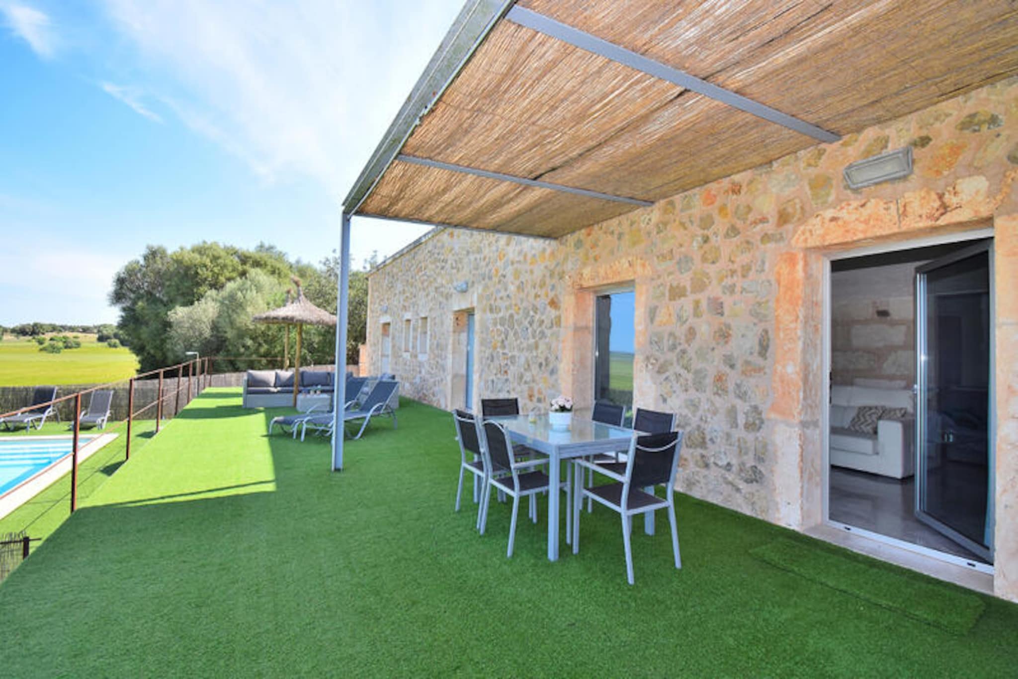 In the heart of Mallorca’s countryside, this stunning villa in María de la Salut invites you to experience the island’s serene beauty. Surrounded by rolling fields and just a short drive from pristine beaches, this property offers the perfect blend of rural charm and modern comfort. Wake up to the gentle sounds of nature and enjoy panoramic views of the mountains and lush gardens from your private terrace. Whether you’re seeking a peaceful retreat or a base to explore Mallorca’s treasures, this villa is a haven of tranquility. \n\nSpanning 250 m², the villa accommodates up to six guests across three spacious bedrooms. The interiors are thoughtfully designed with contemporary furnishings and warm touches, ensuring a cozy yet sophisticated atmosphere. The fully equipped kitchen makes meal preparation a delight, while the airy living spaces are perfect for unwinding after a day of adventure. Step outside to discover a private swimming pool, a barbecue area, and ample seating for al fresco dining under the Mediterranean sky. With air conditioning, Wi-Fi, and satellite TV, every detail has been considered for your comfort. \n\nLocated just 900 meters from the charming village center, you’ll find local shops, restaurants, and a bus station within easy reach. For beach lovers, the golden sands of Playa de Muro are only 15 km away, while the rugged beauty of Son Serra de Marina is a short drive further. Golf enthusiasts can enjoy the Pollensa Golf course, and the nearby train station in Muro provides convenient access to explore the island. María de la Salut is an ideal destination for families and those seeking an authentic Mallorcan experience. \n\nEscape the ordinary and immerse yourself in the timeless allure of Mallorca. Whether you’re relaxing by the pool, exploring nearby villages, or savoring local cuisine, this villa offers an unforgettable holiday experience. Let the charm of María de la Salut captivate you and create memories that will last a lifetime.