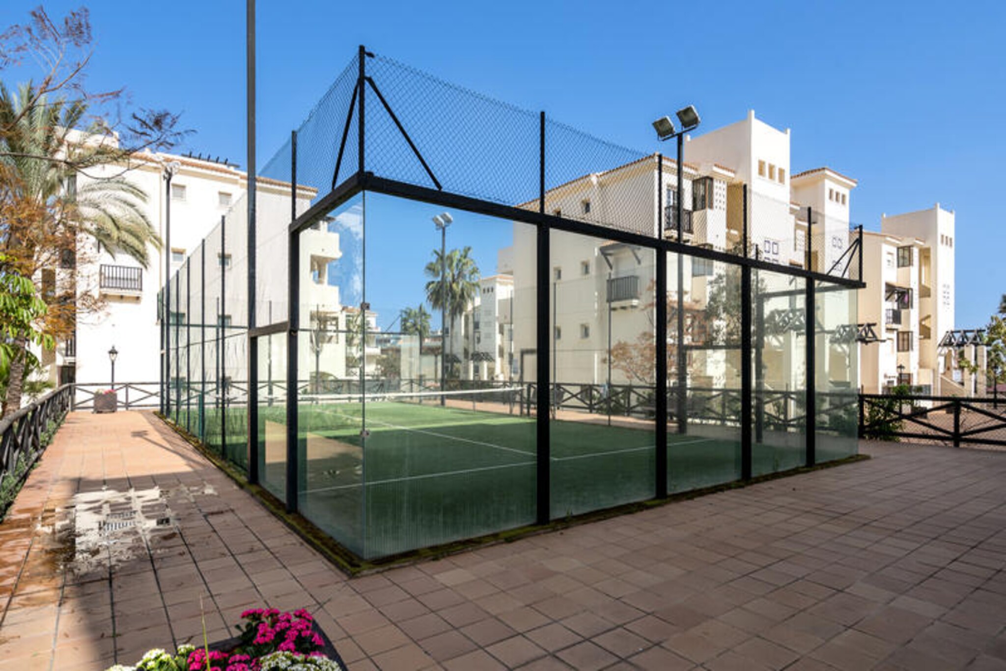 In the charming town of San Luis de Sabanillas, this modern and inviting apartment offers a serene retreat for families and groups of up to six guests. Surrounded by lush gardens and overlooking the pristine Duquesa Golf course, the property combines contemporary comfort with a tranquil setting, perfect for unwinding after a day of exploration. Whether you're seeking a relaxing getaway or an active holiday, this residence provides the ideal base for your Costa del Sol adventure. \n\nThe apartment spans 81 m² and features two spacious bedrooms, a bright living area, and a fully equipped electric kitchen complete with a refrigerator, microwave, oven, and dishwasher. Step out onto the expansive 50 m² terrace, furnished for alfresco dining, and soak in the views of the landscaped gardens. Modern amenities such as Wi-Fi, satellite TV, air conditioning, and central heating ensure a comfortable stay, while thoughtful extras like a washing machine, iron, and hairdryer cater to your convenience. Guests can also enjoy the shared swimming pool and paddle tennis court within the residential complex, adding a touch of leisure to your stay. \n\nLocated just 300 meters from local restaurants and cafes, and a short stroll to the Mercadona supermarket, everything you need is within easy reach. The sandy shores of Playa De La Colonia are only 2 kilometers away, perfect for sunbathing or enjoying water sports. Golf enthusiasts will appreciate the proximity to Duquesa Golf, while the vibrant town center of Sabanillas offers charming shops and a welcoming atmosphere. For those arriving from afar, Malaga Airport is conveniently located 100 kilometers away. \n\nWhether you're drawn to the golden beaches, the lush fairways, or the vibrant local culture, this apartment invites you to experience the best of southern Spain. Relax, explore, and create lasting memories in this delightful coastal haven.