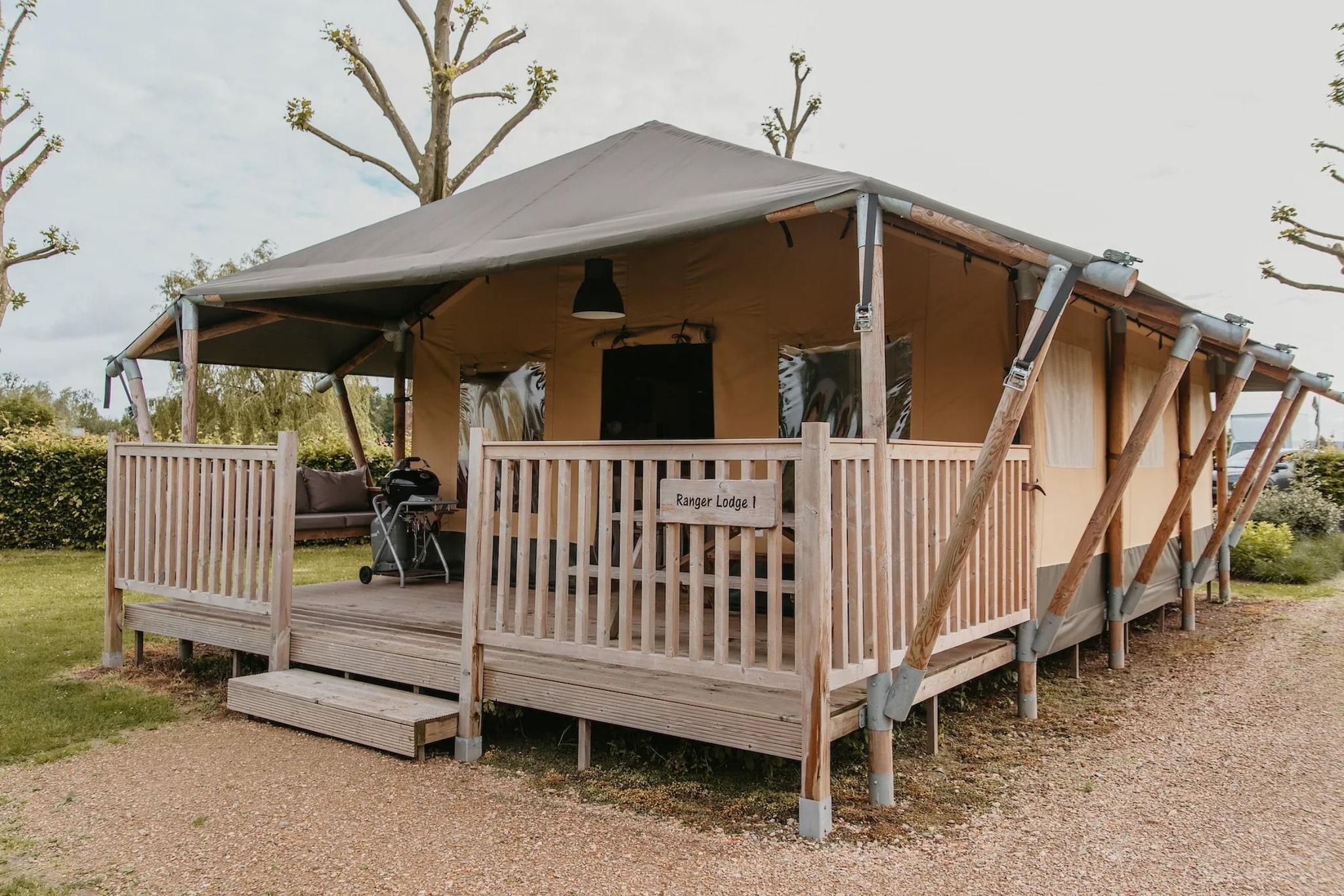 Imagine waking up to the gentle ripple of water and sunlight filtering through the canvas of your camp, that’s how a day begins at a Ranger Lodge, placed inside De Betuwse Hofjes. This peaceful glamping retreat blends the charm of the wild with the comfort of a fully equipped home, making it ideal for those craving a slower pace.

Inside, the lodge offers a warm, compact layout - a living space to gather or dine in for meals, a fully equipped kitchen for easy cooking, two bedrooms – one with a double bed and a bunk bed, and the other has a bunk bed, sleeping 6 guests easily, and a private bathroom for complete privacy. The covered veranda becomes your favourite corner for morning coffee, afternoon reading sessions, or calm evenings listening to the wind drift through the trees.

Around you, the estate feels like a living postcard. A swimming lake with a sandy shore, calm fishing spots, green paths, and small play areas brings a sense of freedom to your stay. Whether you swim, wander barefoot along the edge, try the air-trampoline or simply soak in the quiet, every moment feels refreshingly uncomplicated.

Hop on a bike to explore the region, gliding through orchards, riverbanks, village cafés and the wide, open Dutch countryside. With free parking and Wi-Fi, you can plan as much or as little as you want.

Nights here are easy as you savour shared dinners outdoors, long conversations under warm light, and the kind of rest that only nature can offer.