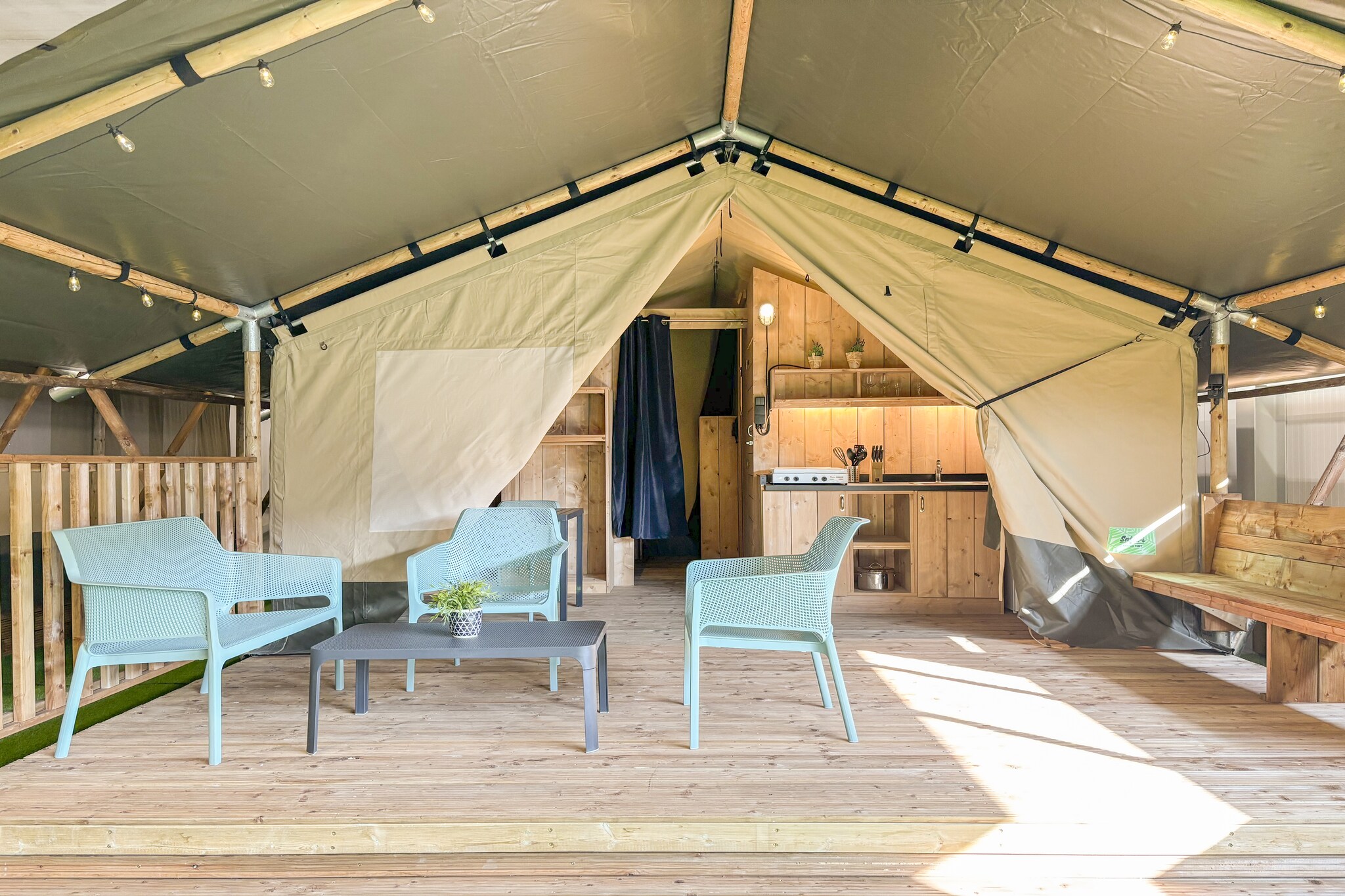 Tucked between orchards and quiet lakes, the Blossom tent in the camping pitch feels like a snug natural escape within the Dutch countryside - peaceful enough to doze off, yet comfortable enough to make you seamlessly adapt to outdoor living. Whether you arrive as a couple or with friends, this camp gives you space to loosen up and enjoy life outdoors.

Inside the tent, you will only have a simple sleeping arrangement with two bedrooms furnished with a double bed or two single beds and a bunk bed, respectively, and a private bathroom with essentials, rest all the other areas of the house count as outdoors, consisting of an actual bright living area flowing into the veranda, and a kitchen with everything needed for shared meals. You get access to Wi-Fi and electricity.

Nature literally surrounds you here. Swim or sunbathe along the sandy beach of the on-site lake, wander the green pathways, or enjoy simple activities like fishing, table tennis, or bouncing around on the air trampoline. It’s all designed to feel light, effortless and fun.

Step outside the estate and the region offers cycling adventures, river walks and charming local villages full of Dutch rural charm. With free parking and easy access to nearby towns, exploring is simple.

Return to the lodge, cook dinner in your open kitchen or enjoy a snack from the park’s small kiosk, then unwind under the starlit sky with calm water in front of you. Blossom camp is where comfort meets countryside - a refreshing camping escape you’ll remember for its peace as much as its simplicity.