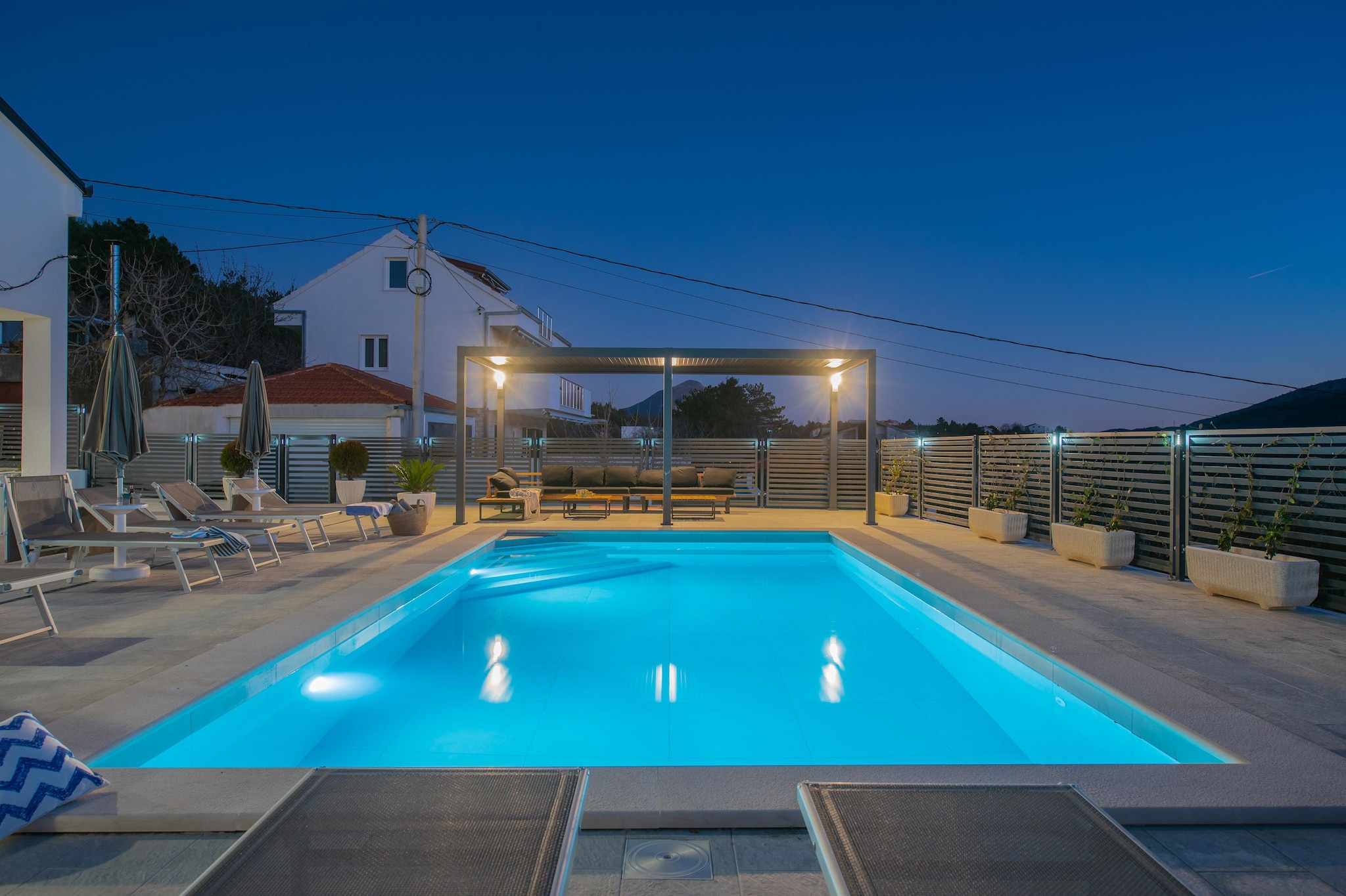 Set in the peaceful village of Tugare, only a short drive from Omiš, Villa Magnolia is designed for families and mixed-age groups who want space, privacy, and easy access to both nature and the coast. Spread across 180 m² on a fully fenced plot, the villa comfortably welcomes up to ten guests with a layout that supports both together-time and quiet corners.

At the heart of the garden sits a large private swimming pool, framed by sun loungers, an outdoor shower, and shaded seating - all visible from the living areas for easy supervision with kids. Fitness equipment and other activities keep energy balanced throughout the day, while the outdoor dining terrace with a barbecue turns evenings into relaxed family dinners under the stars.

Inside, the villa is bright, practical, and well-zoned. The ground floor features an open-plan living and dining space - a single sofa bed, a TV, a PS5, and a fully equipped modern kitchen. Two double bedrooms and a bathroom sit on this level, along with a laundry room for longer stays. Upstairs, a second kitchen and lounge with another single sofa bed, a terrace, two additional double bedrooms, and another bathroom create a flexible dual-living setup that works especially well for families with older children or grandparents.

Daily essentials - minimarket, café, fast food, and local taverns are all within walking distance. The nearby Cetina River offers rafting, zip-lining, and boat rides, while beaches near Omiš are an easy drive away. A cultural day trip to Split adds history, shopping, and seaside promenades to the mix.

Villa Magnolia is best suited for families who want a safe private pool setting, walkable daily amenities, space to spread out, and fast access to beaches, river adventures, and city life - without giving up the calm of a true village stay.