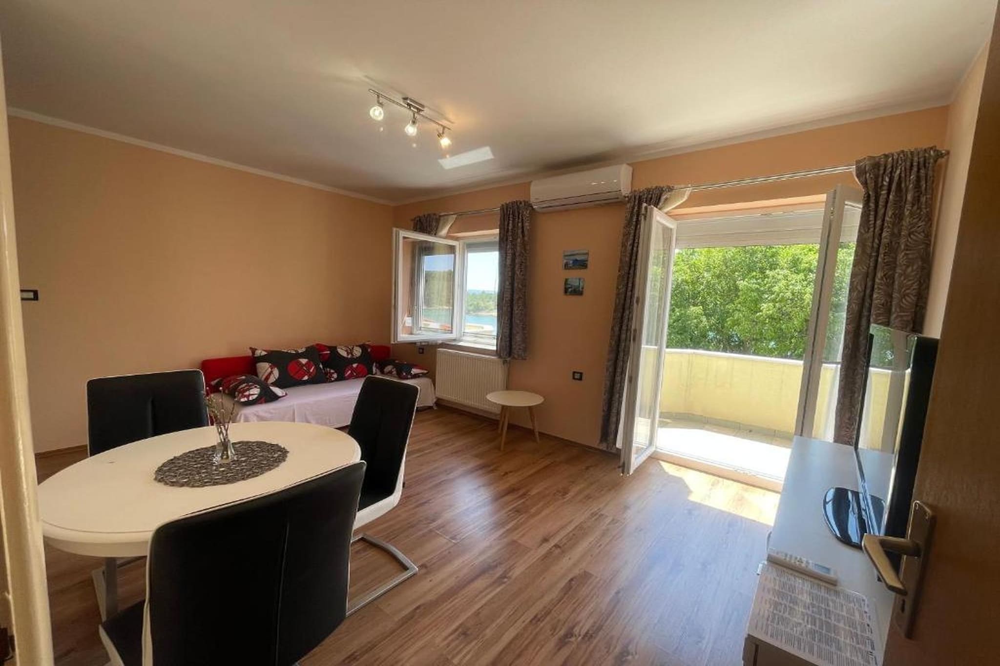 This stylish apartment is a wonderful choice for up to three guests seeking comfort, privacy, and beautiful sea views along the Adriatic coast. Designed with modern interiors and a calm, coastal feel, the apartment opens onto a private balcony where the blue of the sea meets the rugged mountain backdrop. It’s the perfect spot to enjoy a slow breakfast, read a book, or simply take in the fresh air.
Inside, the apartment feels bright and thoughtfully arranged. The living room offers a comfortable seating area with a sofa bed, a dining table for shared meals, and a flat-screen TV with satellite channels for relaxed evenings. The separate bedroom features a cosy double bed for restful nights, while air conditioning and soundproofing ensure comfort in every season. The private bathroom is modern and practical, complete with a shower or bath, fresh towels, a hairdryer, and essential amenities.
The apartment’s location makes it easy to enjoy both nature and local life. Several lovely beaches are nearby for swimming and sunbathing, while scenic coastal paths invite gentle walks with sea views. Local restaurants and cafés are within easy reach, offering regional dishes and relaxed dining by the coast. Whether you’re planning beach days, short excursions, or simply time to unwind, this apartment offers a balanced blend of modern comfort, stunning views, and an easygoing seaside atmosphere.