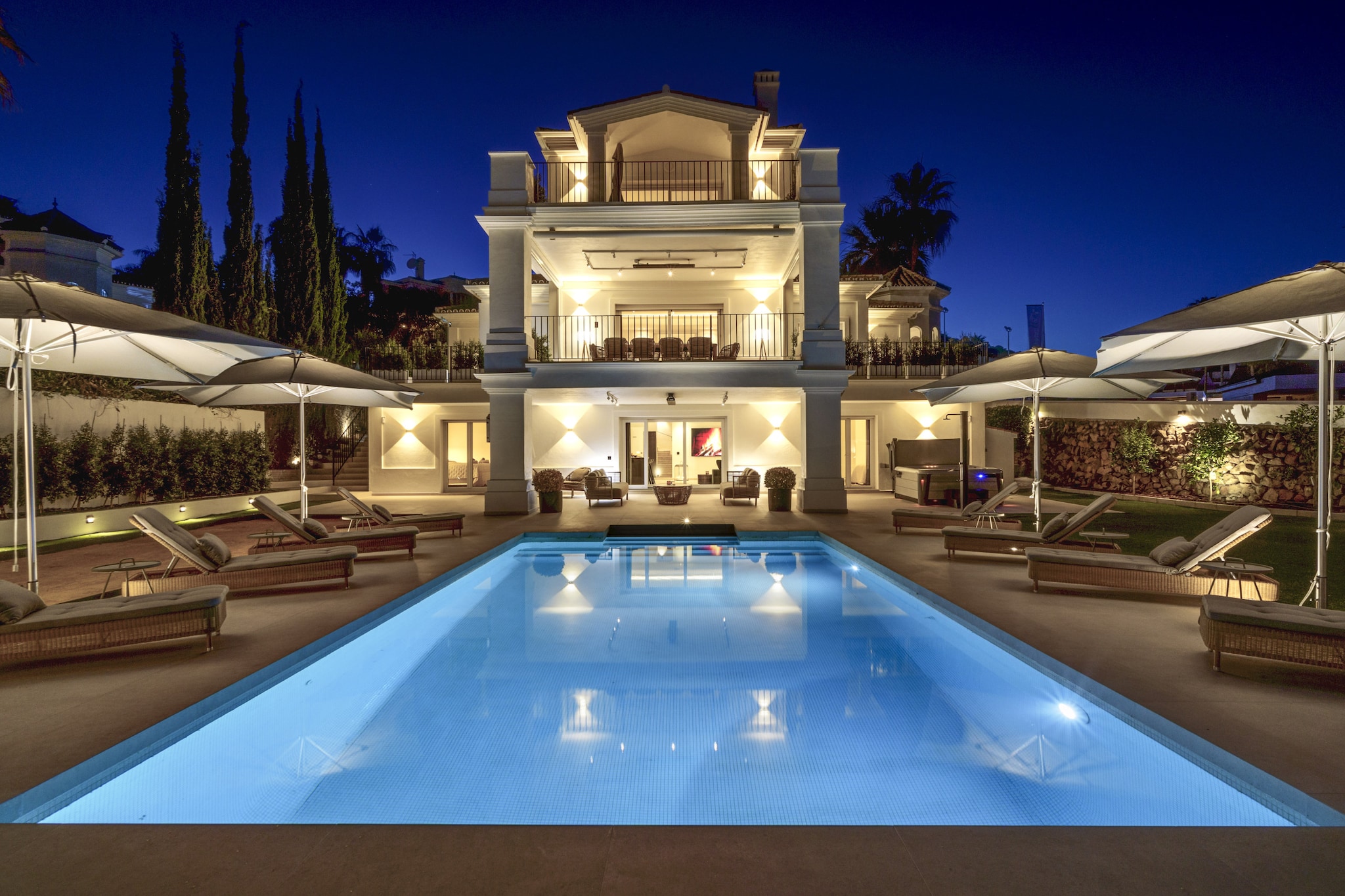 Located in Marbella’s sought-after coastal surroundings, this expansive villa offers a luxurious private retreat for up to twelve guests seeking comfort, privacy and relaxation on Spain’s Costa del Sol. Designed across three levels with lift access, the property provides an ideal setting for extended family holidays or group getaways within convenient reach of beaches, golf courses and local amenities.

Inside, the villa features six generously sized bedrooms arranged across different levels to ensure flexible group accommodation. One en-suite bedroom is situated on the ground floor alongside the open-plan living area and fully equipped kitchen, while the second floor hosts three additional bedrooms with direct terrace access. The basement level includes two further bedrooms together with a dedicated spa area. Four bathrooms and a separate guest toilet support everyday convenience, while the modern kitchen allows for easy self-catering throughout your stay. Underfloor heating is also available, ensuring indoor comfort during cooler months.

Guests can step outside onto multiple terraces overlooking the landscaped garden and private swimming pool. A spacious outdoor dining area seating up to twelve people and a gas barbecue create an ideal setting for alfresco meals. The rooftop terrace features a lounge and bar area along with an outdoor Jacuzzi, offering open views of the Mediterranean Sea and surrounding mountains.

Located within driving distance of Marbella’s beaches, golf clubs and marina, this villa provides year-round opportunities for seaside relaxation and exploring the Costa del Sol’s natural landscapes and cultural attractions.