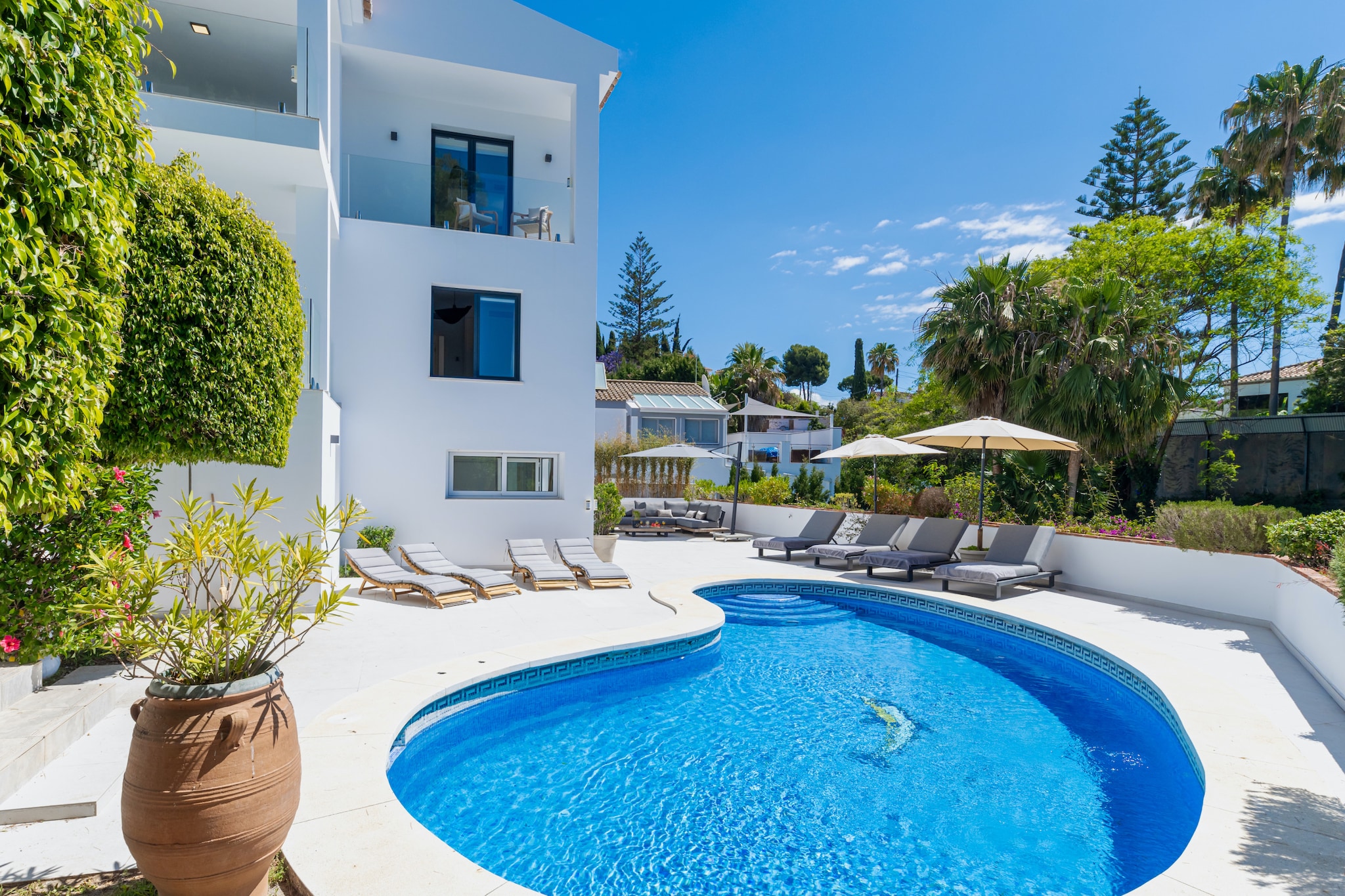Set in the peaceful suburb of El Rosario in Marbella, Spain’s Costa del Sol, this five-bedroom villa accommodates up to ten guests just minutes from sandy beaches and coastal attractions. Surrounded by landscaped gardens with panoramic Mediterranean views, it blends elegant interiors with generous outdoor space - ideal for families or groups seeking comfort near Marbella’s lively centre.

The upper level features a bright open-plan living and dining area with a fully equipped modern kitchen including refrigerator, oven, microwave, dishwasher, freezer and wine cooler. A bedroom with a private en-suite bathroom adds convenience. Large glass doors lead to a shaded terrace overlooking the pool and garden, perfect for outdoor dining.

On the lower level, the master suite offers a private terrace and an en-suite bathroom with a bathtub and a separate shower. Another bedroom with its own bathroom is also located here. An independent guest apartment provides two additional bedrooms with direct access to the pool area, offering extra privacy for part of the group. Multiple modern bathrooms ensure comfort for larger parties.

Outside, the south-facing swimming pool and jacuzzi enjoy sun throughout the day, complemented by quality loungers and a barbecue area for relaxed alfresco living. Located around 7 km from Marbella’s Old Town and close to beach clubs, restaurants, and golf courses, this villa combines privacy, sea views, and easy access to the best of the Costa del Sol.