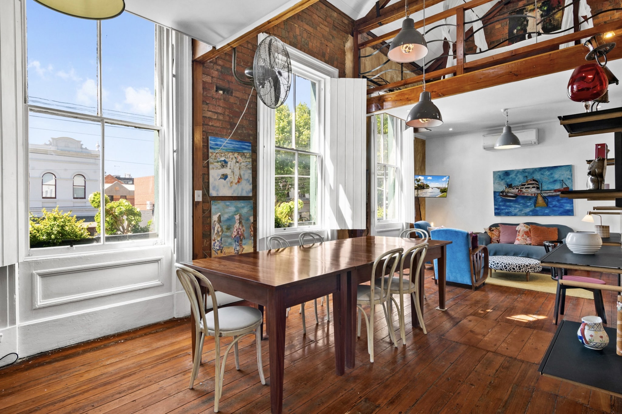 Property description
Stay in a true piece of Melbourne history at The King Arms Hotel (est. 1857), now a light-filled two-mezzanine-bedroom open-plan loft in North Melbourne. Three heritage sash windows open wide, overlooking Queensberry Street cafés and welcoming warm morning sun. Exposed brick and timber beams meet modern comfort, with two living areas, two bathrooms, two queen mezzanine bedrooms, a sofa bed, full kitchen, dining by the windows, smart TV and fast Wi-Fi throughout.
The space
Spanning two levels, the residence showcases exposed brick walls, timber beams, and polished wooden floors that enhance its heritage character while maintaining a warm, contemporary feel.
 
The ground-floor living area is an inviting space styled with eclectic artwork. It includes comfortable seating for four, a theatre-size smart TV, a fully equipped bathroom, and a sofa bed for additional guests.
 
Upstairs, the main living and dining area seats six and flows seamlessly into a fully equipped kitchen with a gas stovetop, electric oven, and essential cookware. Layered rugs, a rustic coffee table, Art Deco lounges for relaxing, and natural décor accents add warmth and charm throughout.
 
Above, high ceilings and exposed timber trusses frame the two open-plan mezzanine-level bedrooms, each featuring a king-sized bed and roof windows that allow additional natural light to filter through the upper level. Both bathrooms are fully fitted with walk-in showers and modern amenities for comfort and convenience.
 
An outdoor courtyard, accessed from the living room, provides a private setting with full outdoor furniture—perfect for leisurely mornings in the sun or relaxed evenings.
 
For added comfort, the property is prepared with professional-grade, hotel-style linen, including a premium three-sheet setup to ensure a fresh, hygienic, and luxurious sleep experience. High-speed Wi-Fi and full streaming access allow you to unwind after a day exploring Melbourne.
