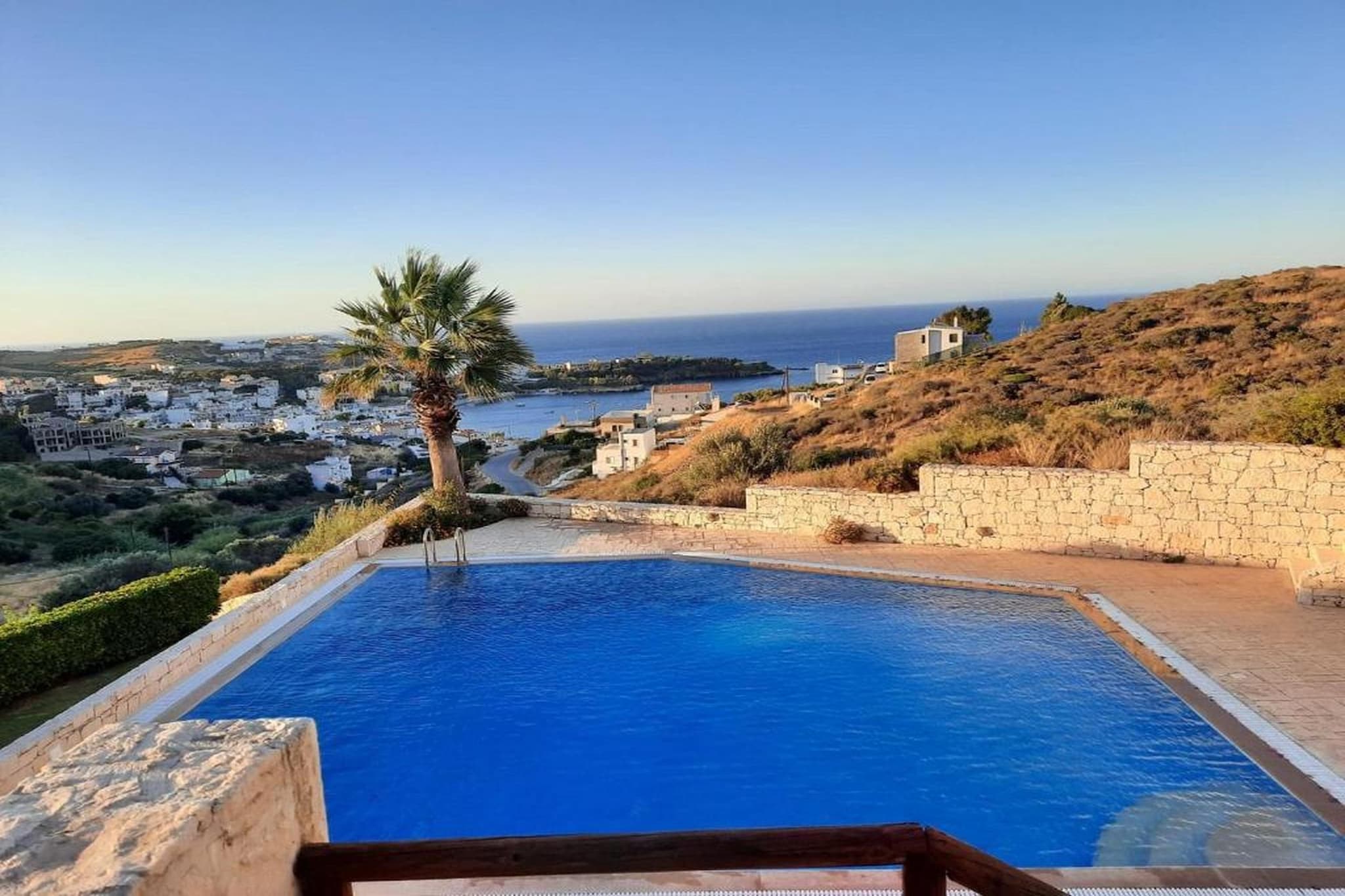 Positioned above the coastline in Agia Pelagia, this villa offers a relaxed setting where sea views and a peaceful atmosphere define the stay. With access to a shared pool and outdoor spaces, it is well-suited for couples or small families looking to enjoy the Cretan coast in a quiet environment.

Inside, the villa features two bedrooms and accommodates up to four guests. Both bedrooms include double beds, creating a clear and comfortable sleeping arrangement. The living area is open and well arranged, with a seating space, a TV and a dining area designed for everyday use. A fully equipped kitchen includes appliances such as an oven, refrigerator, dishwasher and coffee machine, making meal preparation practical. The property also includes two bathrooms with a shower and toilet, offering added convenience for shared stays. Additional amenities such as WiFi, air conditioning, a washing machine and private parking support a comfortable and functional stay.

Outside, the villa opens onto a private terrace with outdoor seating, providing a pleasant space for dining or relaxing while enjoying the surrounding views. Guests also benefit from access to a shared swimming pool set within landscaped surroundings, offering a refreshing option during warmer days.

Located near Agia Pelagia, the villa is within walking distance or a short drive of beaches, local tavernas and coastal paths. Nearby spots such as Lygaria and Psaromoura beaches provide additional swimming options, while Heraklion offers cultural sites, markets and day-trip opportunities across Crete.