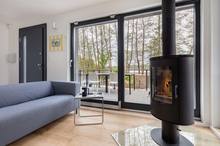 The intimate holiday resort (3 holiday homes) is located in an idyllic area, just 30 m from the shores of Lake WiseÅ‚ka. You can find peace and quiet here, and in the immediate vicinity you can go for a walk or a trip on foot or by bike.

A comfortable, two-story holiday home in a modern, Scandinavian style, with a large terrace overlooking the lake. A complete set of garden furniture awaits you on the terrace. On the ground floor there is a large living room with a fireplace (wood for an additional fee), satellite TV, 2 sofas and a table with chairs. An open, perfectly equipped kitchen. On the ground floor there is also a double bedroom and a bathroom with a shower. On the first floor there are another 2 bedrooms and a second bathroom with a shower. Electric heating (underfloor heating in the bathrooms). Wireless internet is available. The house is surrounded by a well-kept garden, and in it a free-standing sauna (additional fee). There is also a safe parking lot (2 spaces/house). You can rent a grill on site.
The price of your stay includes: bed linen, electricity consumption (in the period 21.06 - 30.08), water consumption, internet, parking (2 spaces per house). Baby cot and high chair on request. 30 m from the holiday home there is a swimming area on the lake, with a small beach. Just 2.5 km away there is also a beautiful Baltic beach. On the other side of the lake (800 m walk) there is a water equipment rental (SUP, water bike, kayak, sailboat). In the center of the town, approx. 900 m from the holiday home, there are 2 grocery and industrial stores and several restaurants. There is also a bike rental. In the nearby area there is the Wolin National Park, with a bison reserve and many hiking and cycling trails.